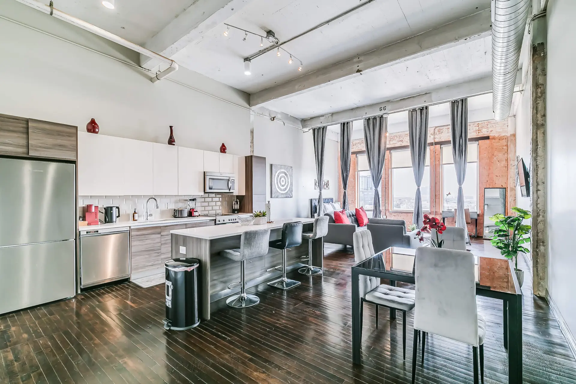 A modern loft apartment with a kitchen, dining area, and living room.