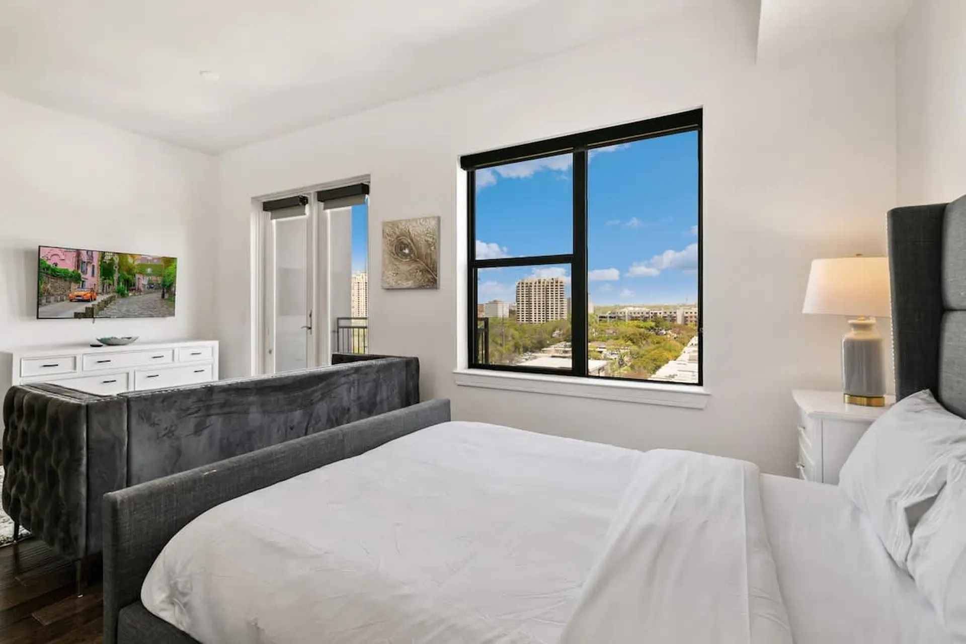 A bedroom with a large window showcasing a city view.