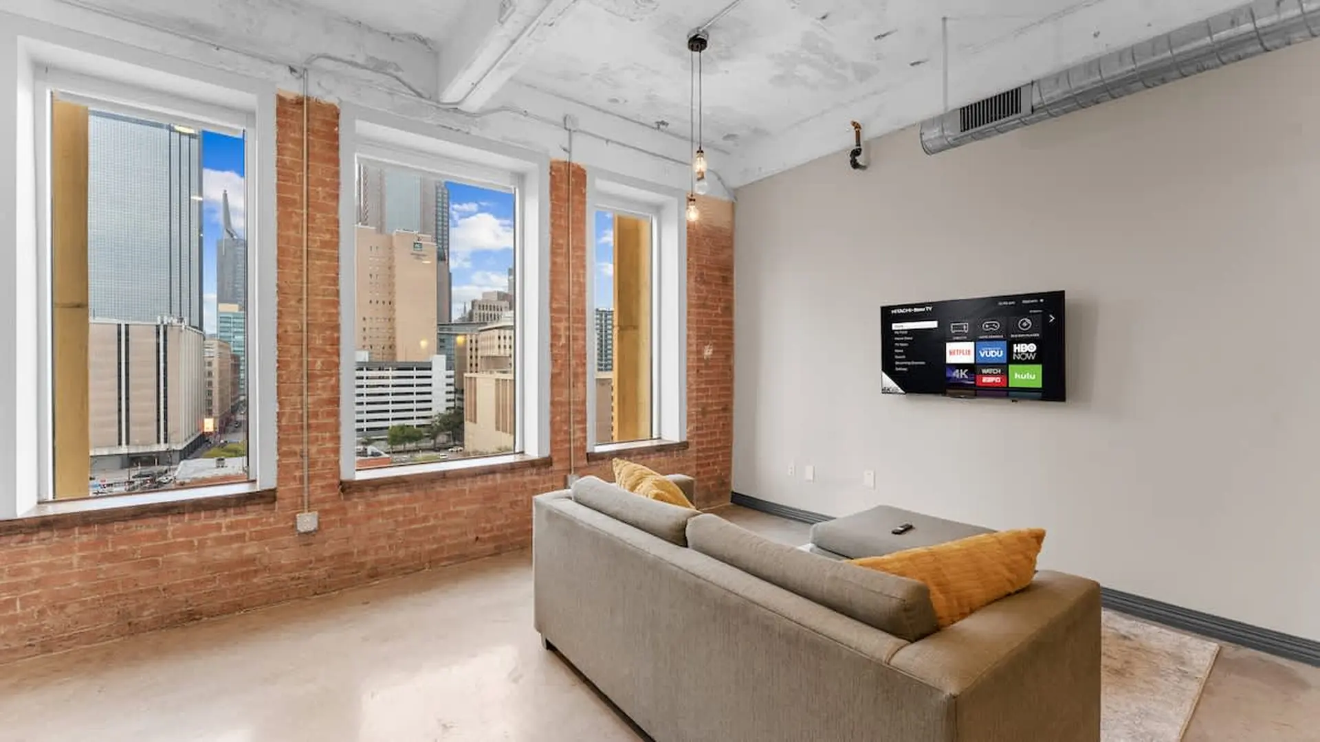 Living room with exposed brick walls, cityscape view, couch, and TV.
