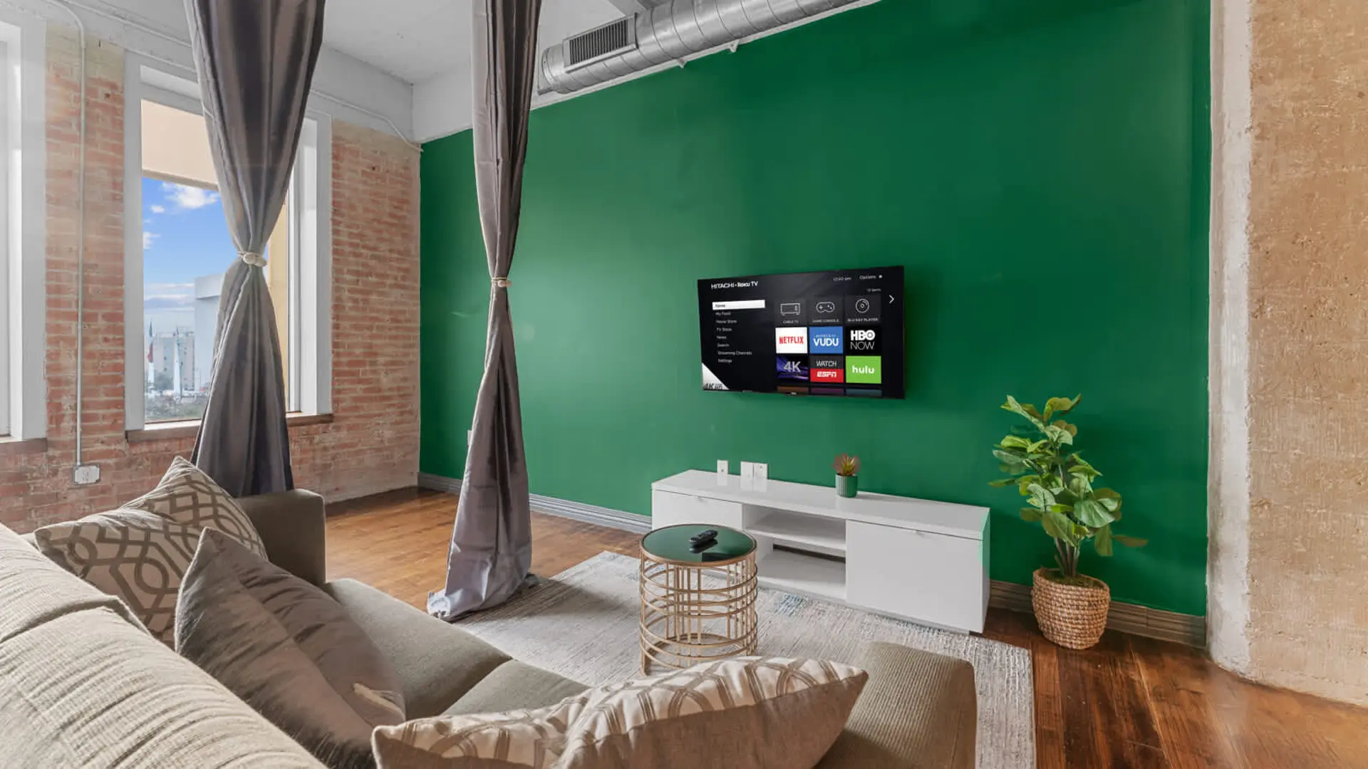 A living room with a green accent wall, a TV, and a couch.