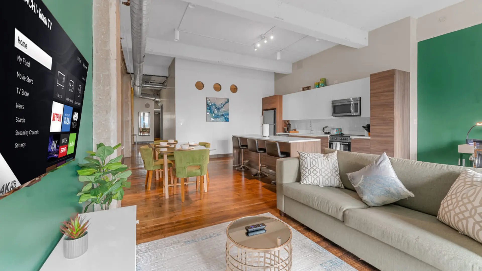 A modern living room with a TV, sofa, kitchen island, and dining area.