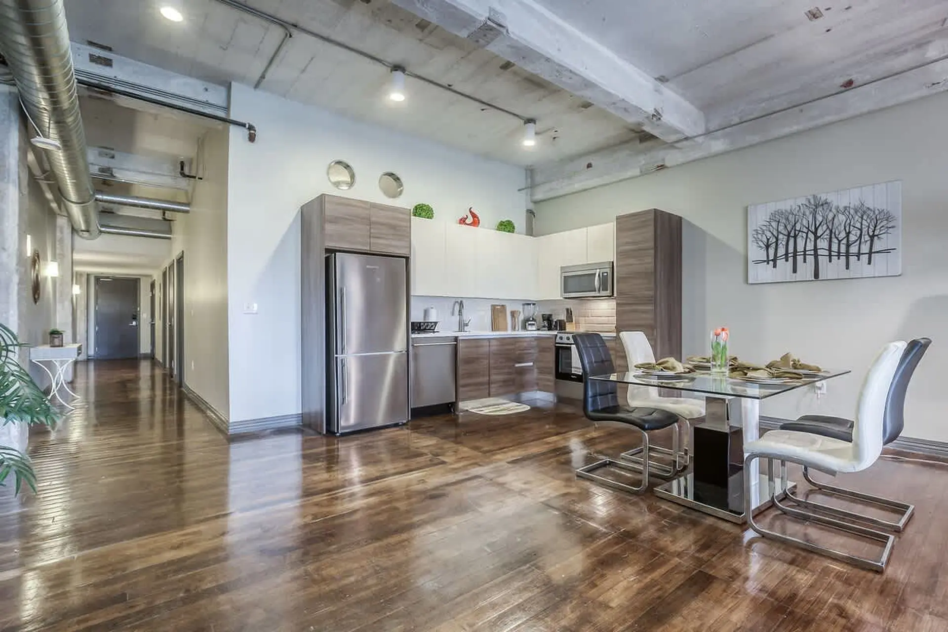 Loft apartment kitchen and dining area with concrete ceiling and hardwood floors.