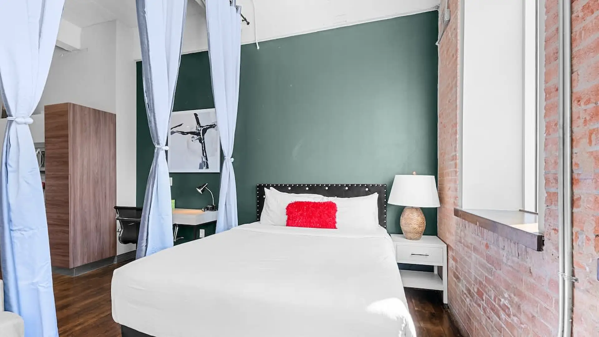 A bedroom with a bed, desk, and wardrobe, decorated with blue curtains.