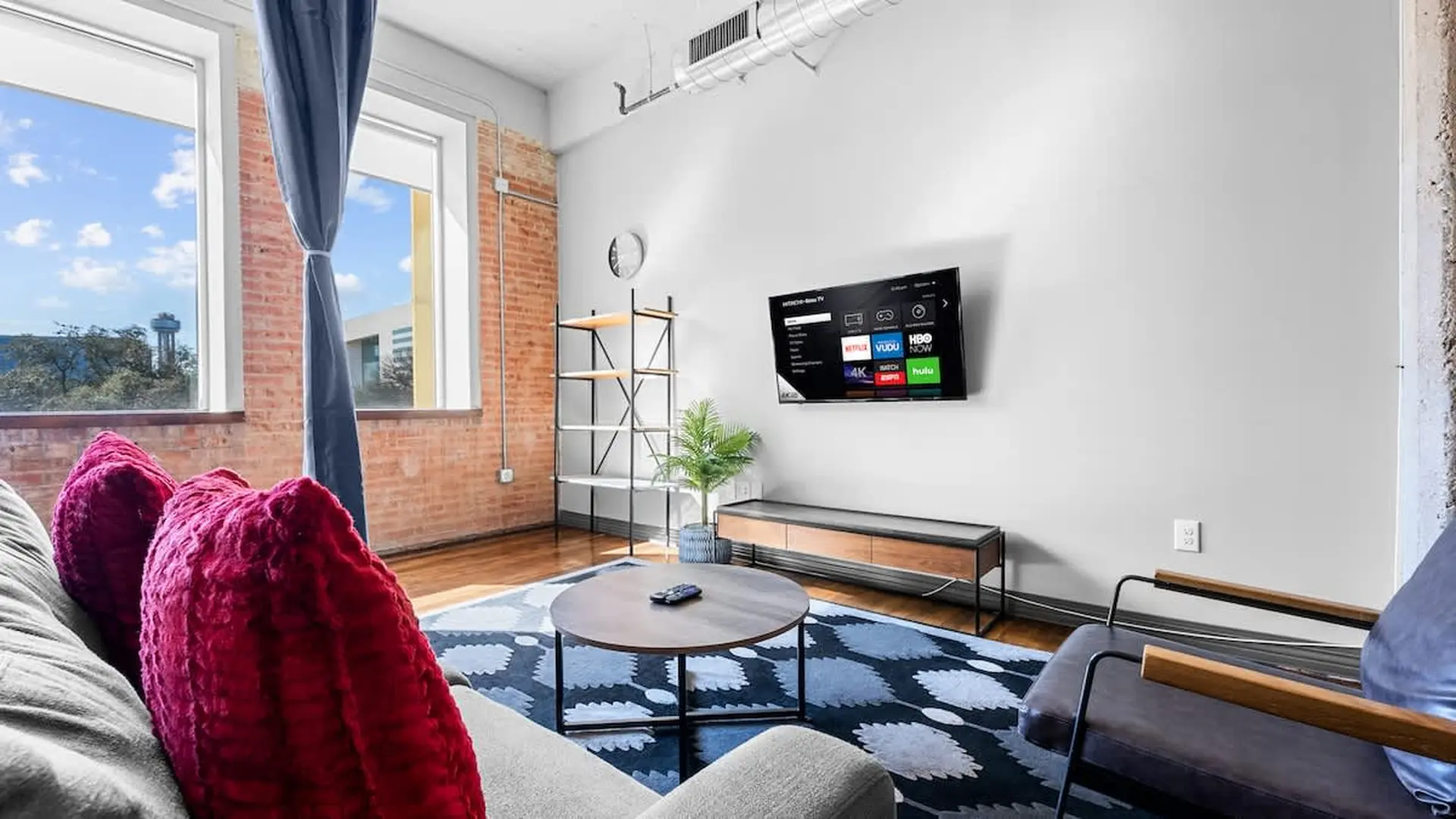 Living room with a TV, couch, coffee table, and large windows.