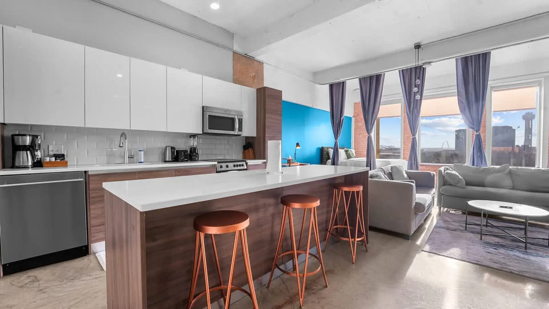 Modern kitchen and living area with island bar and city view.