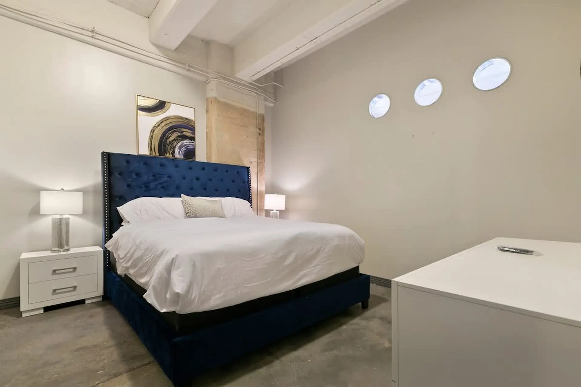 A king-size bed with a navy blue tufted headboard in a modern bedroom.