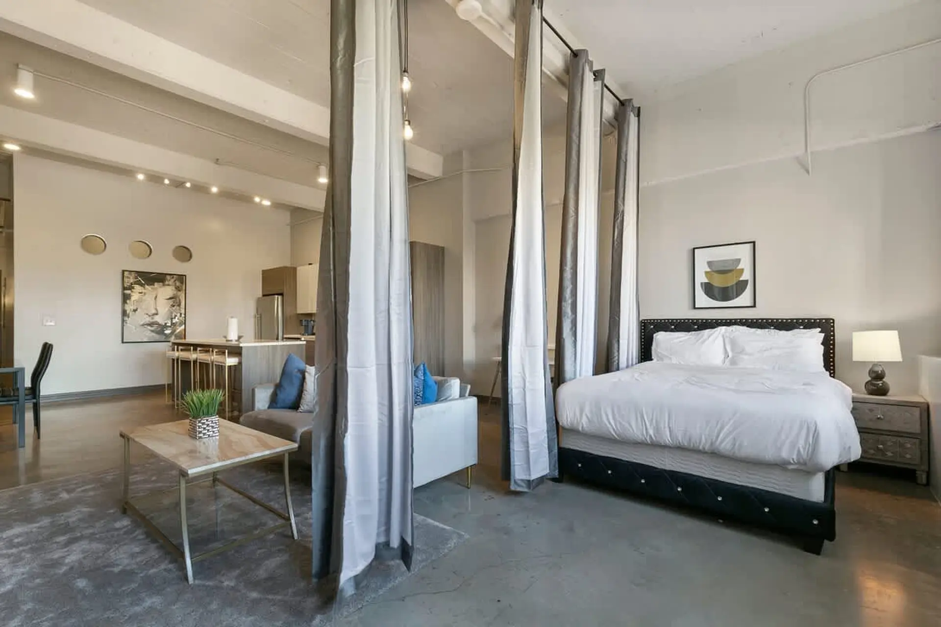 A studio apartment with a living area, kitchen, and bedroom separated by curtains.