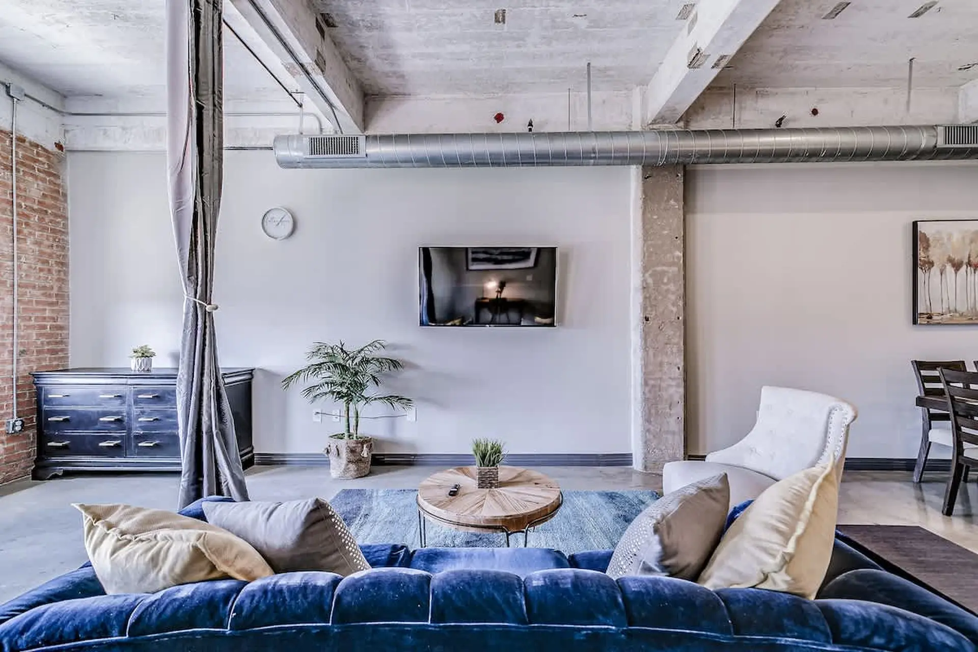 A living room with a blue velvet couch and a rustic coffee table.