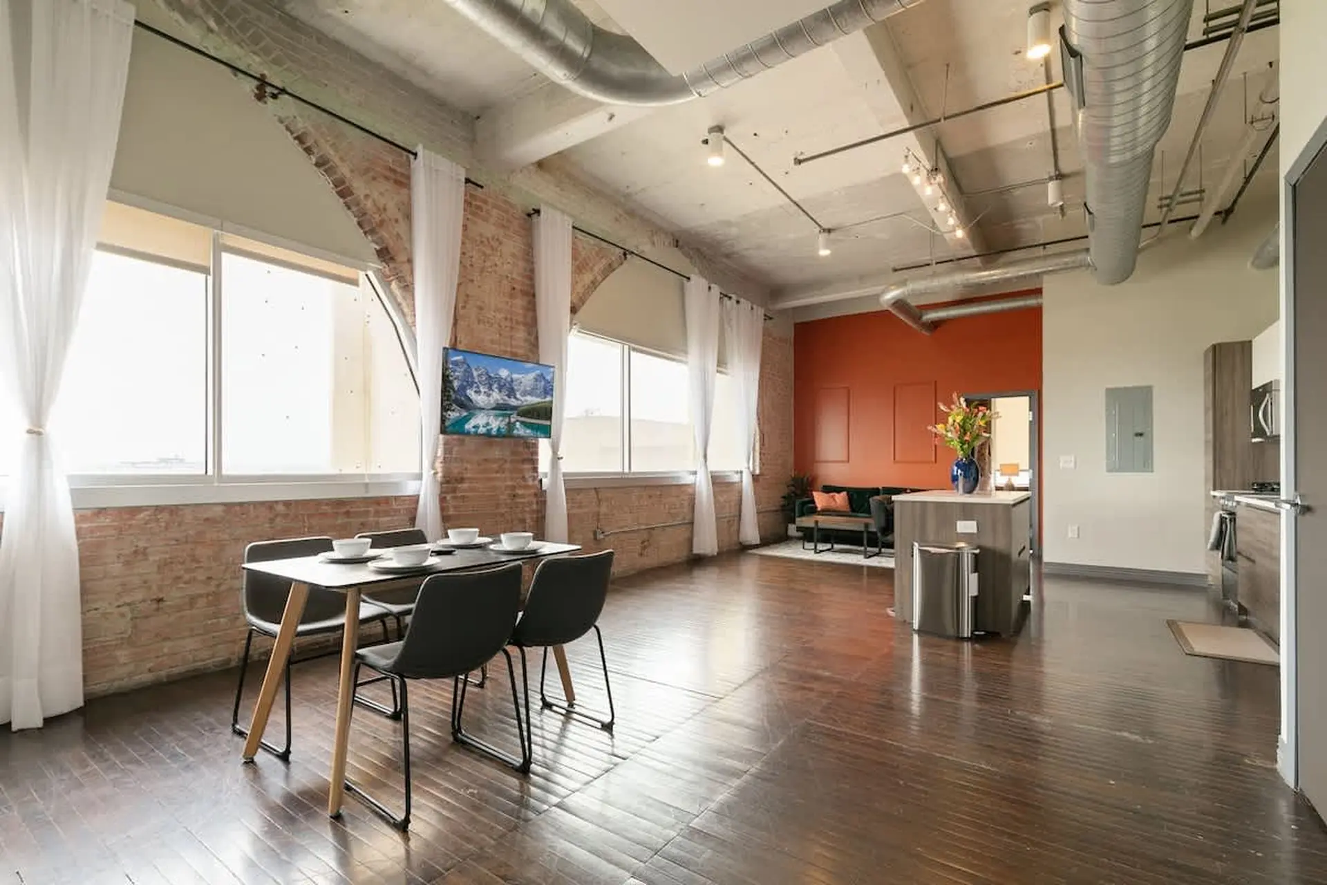 Industrial loft living room and dining area with exposed brick and modern furniture.