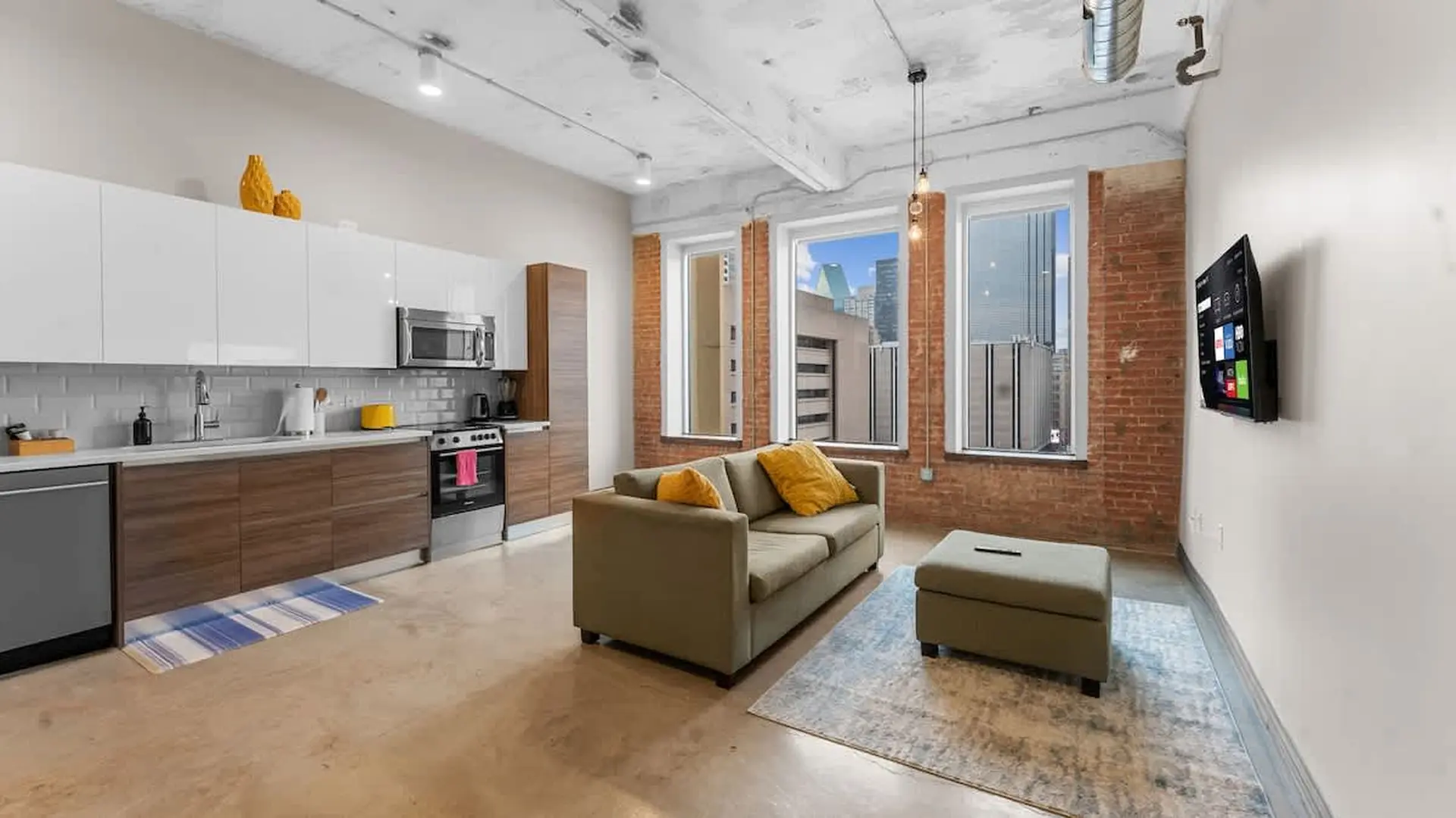 Modern apartment living room and kitchen area with brick walls.