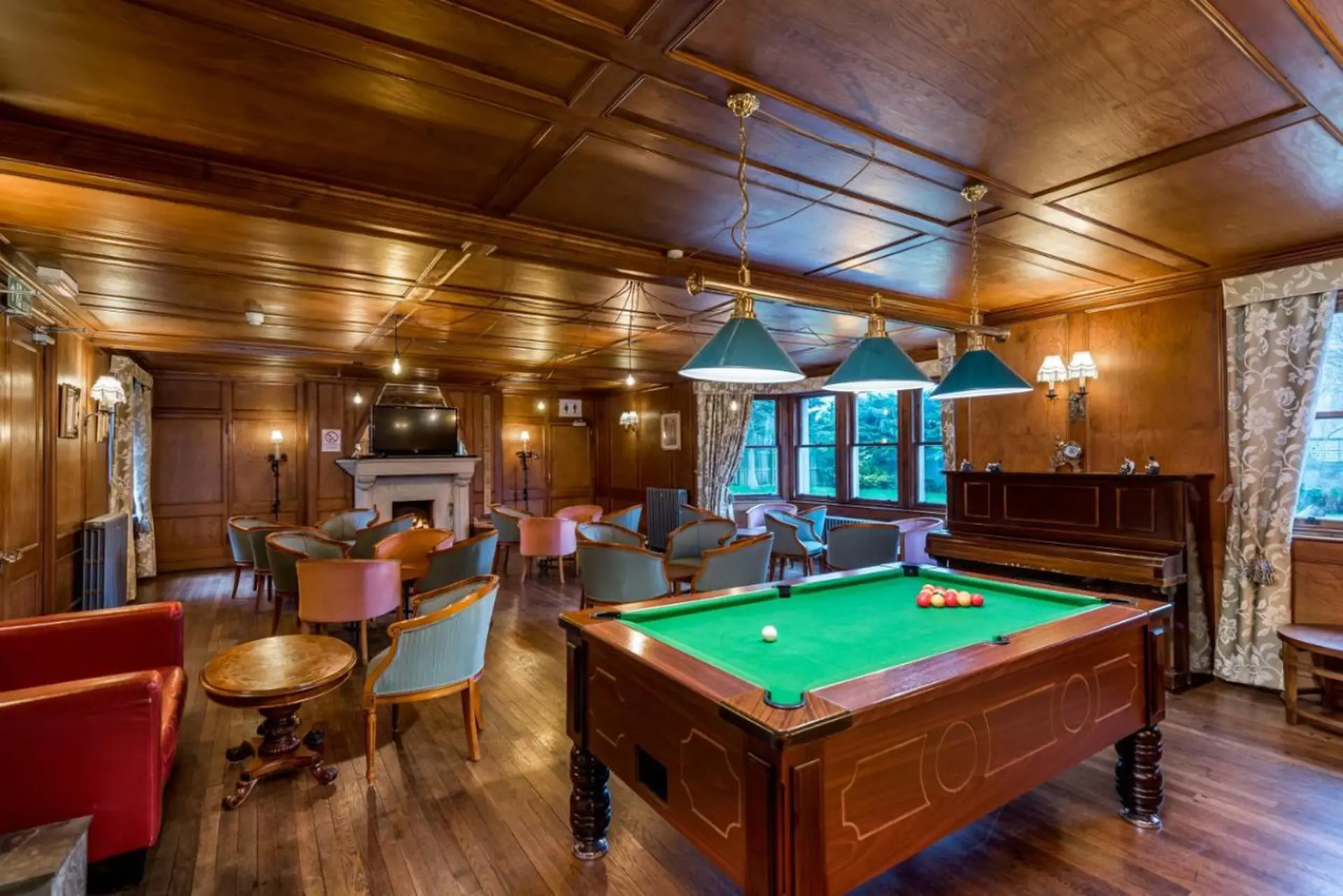 A billiard room with wood-paneled walls and a pool table.