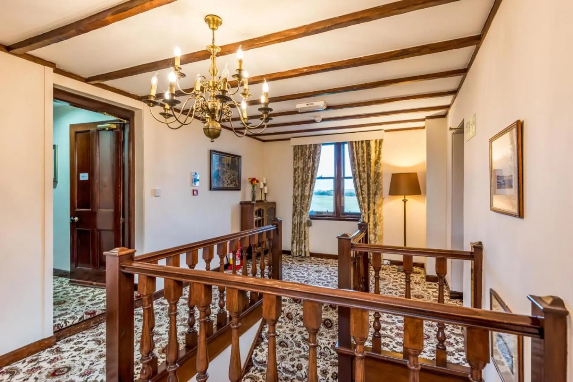 Interior view of a hallway with wooden beams and a chandelier.