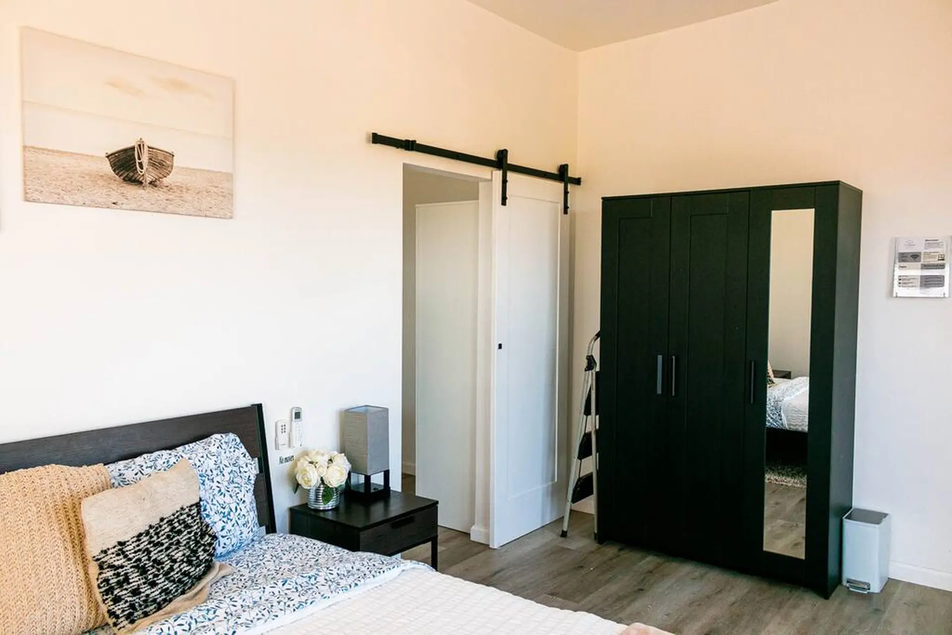 A bedroom with a bed, a dark green wardrobe, and a sliding barn door.