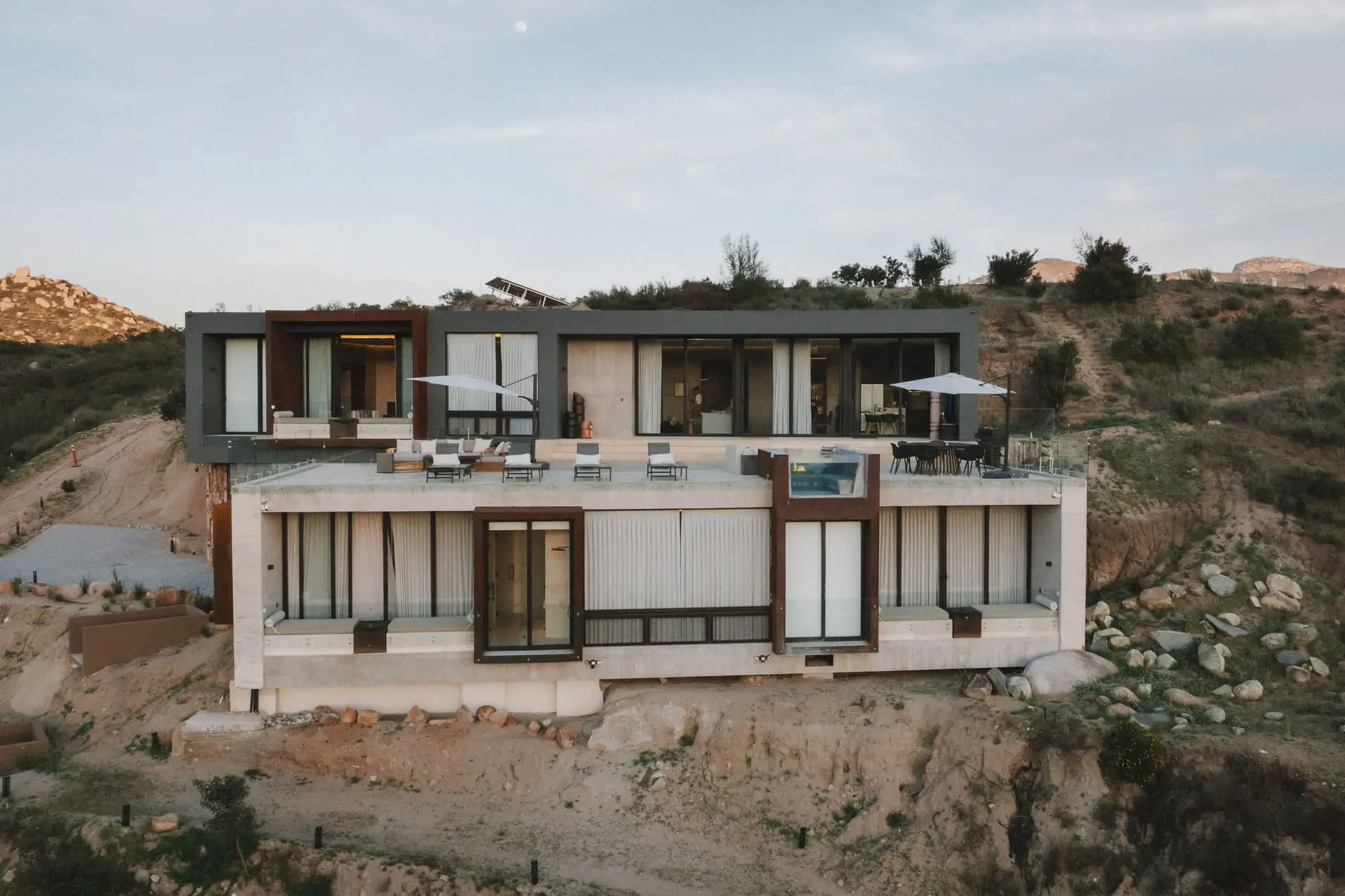 A modern home built into a hillside with a pool and outdoor seating.
