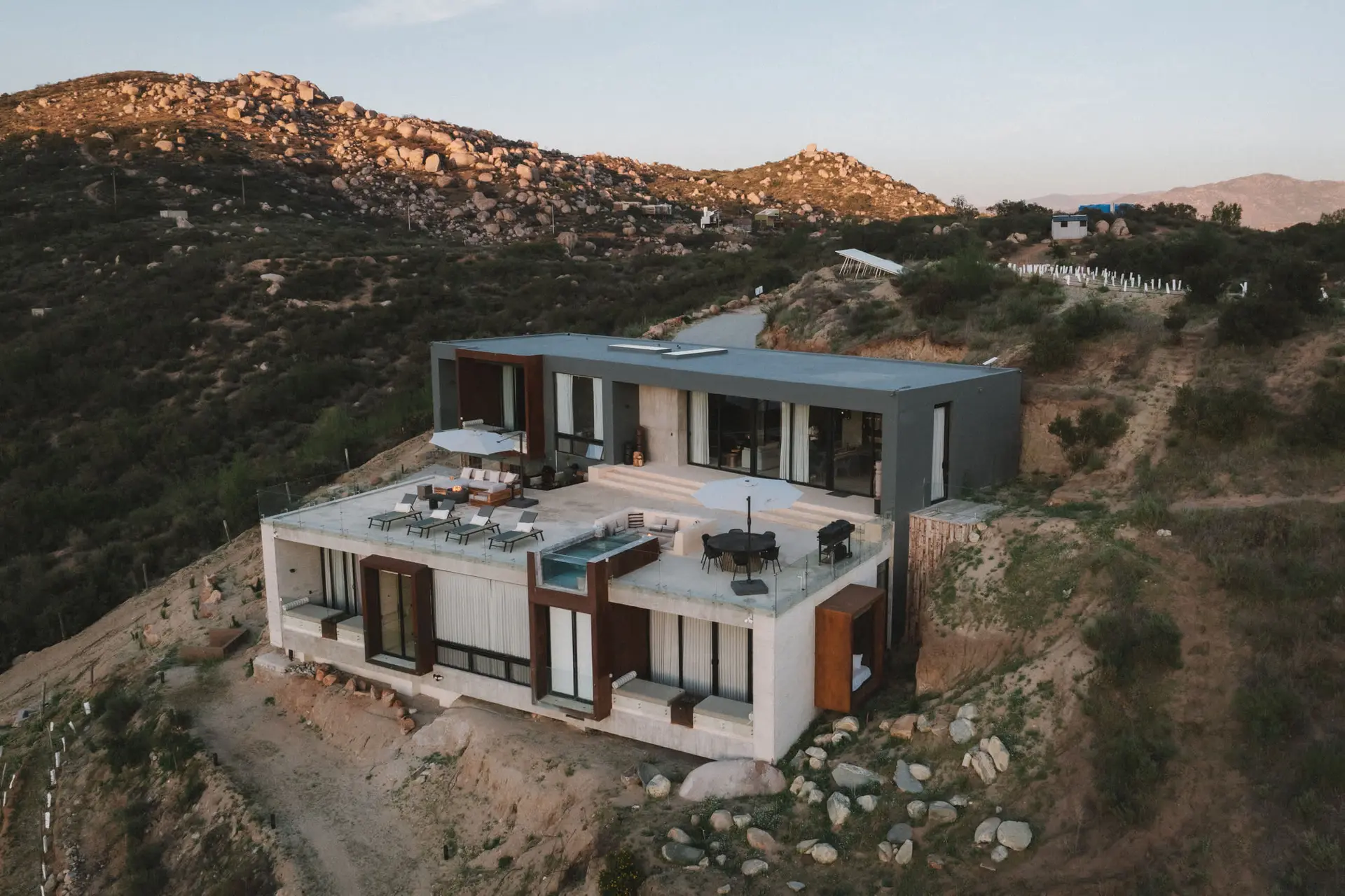 A modern house with a pool and lounge area on a hillside.