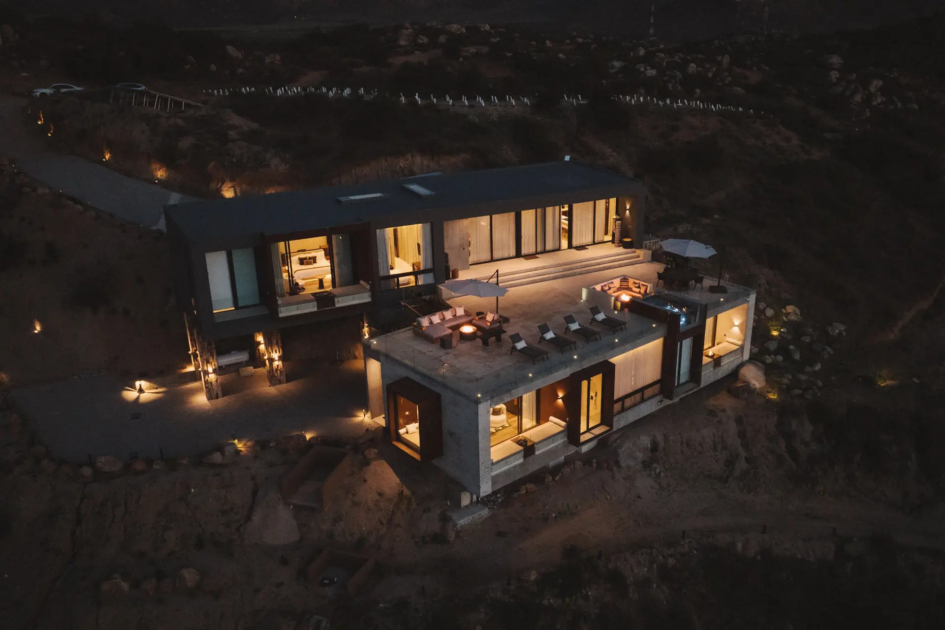 Modern luxury home with pool and fire pit at dusk.