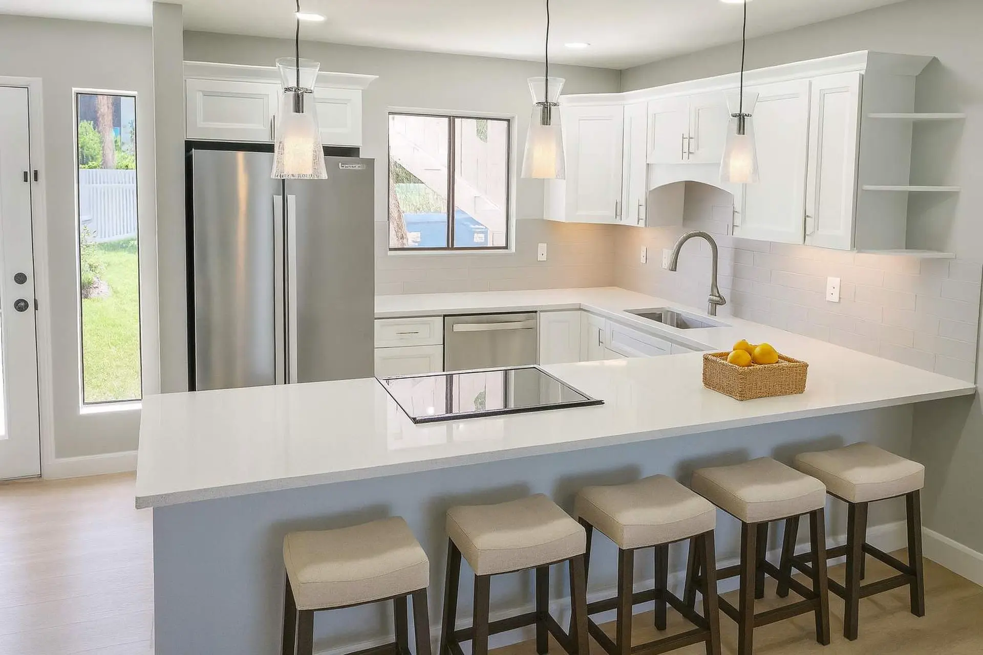 A modern kitchen features white cabinets, stainless steel appliances, and a breakfast bar with stool