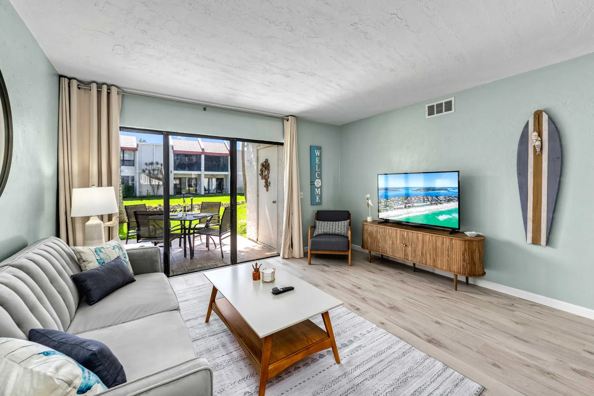 Living room with sofa, coffee table, TV, and patio access.