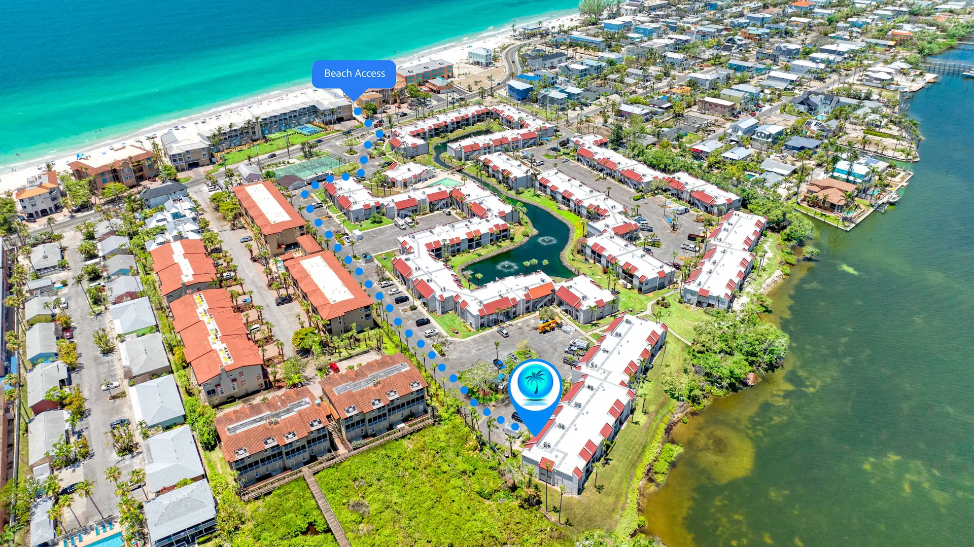 Aerial view of a coastal community with buildings, a canal, and beach access.