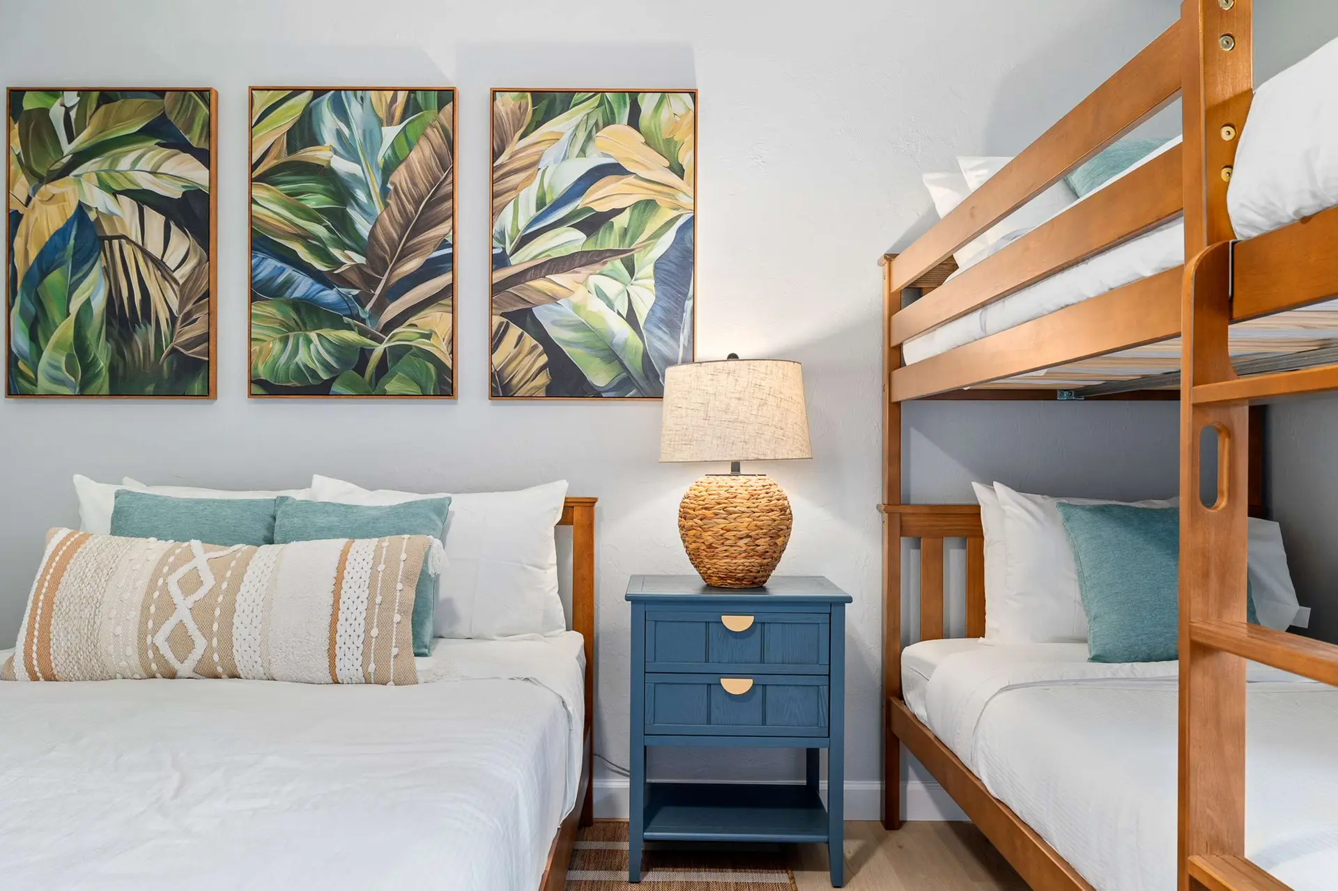 Tropical art adorns the wall above two beds, with a bunk bed to the right.