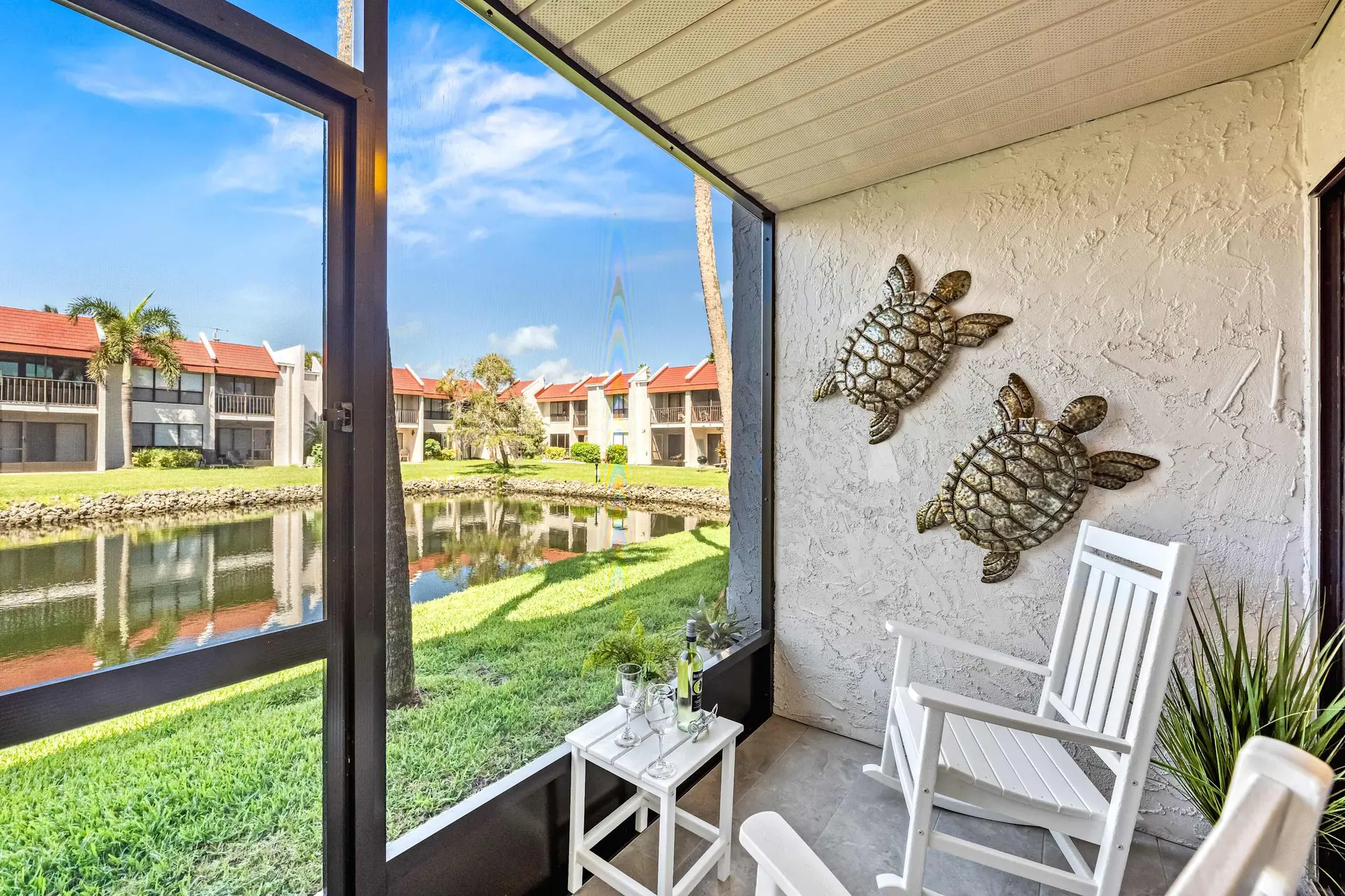 Relaxing screened-in patio with rocking chairs, a pond view, and turtle decor.