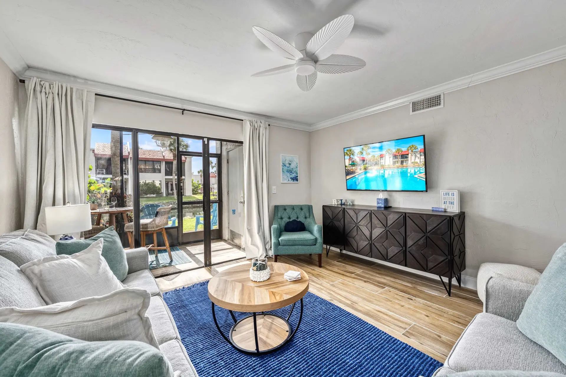 Living room with a blue rug, coffee table, sectional sofa, and a TV.