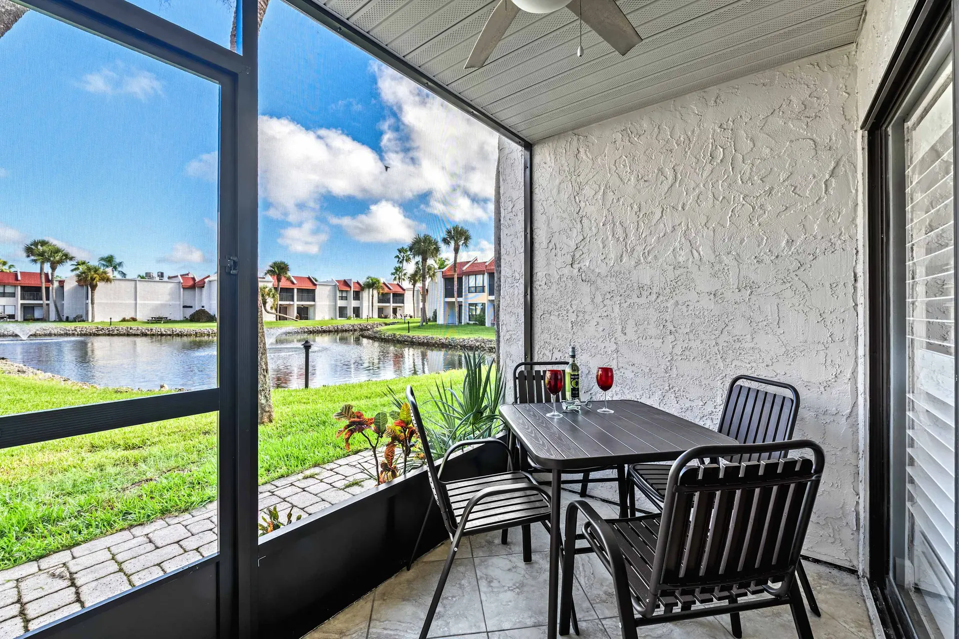 Screened patio with a table, chairs, and a view of a lake and buildings.