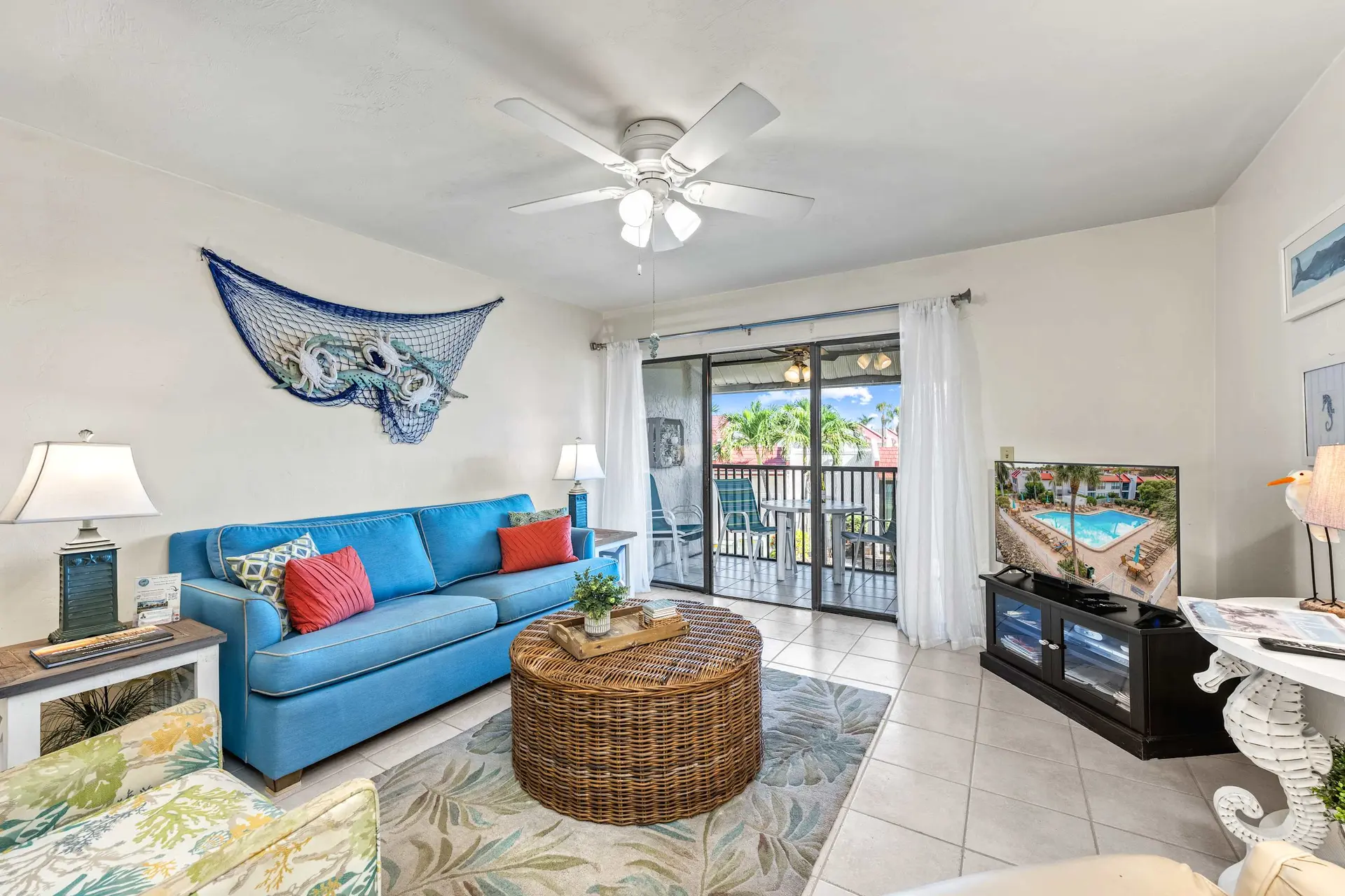 A living room with a blue sofa, wicker coffee table, and TV.
