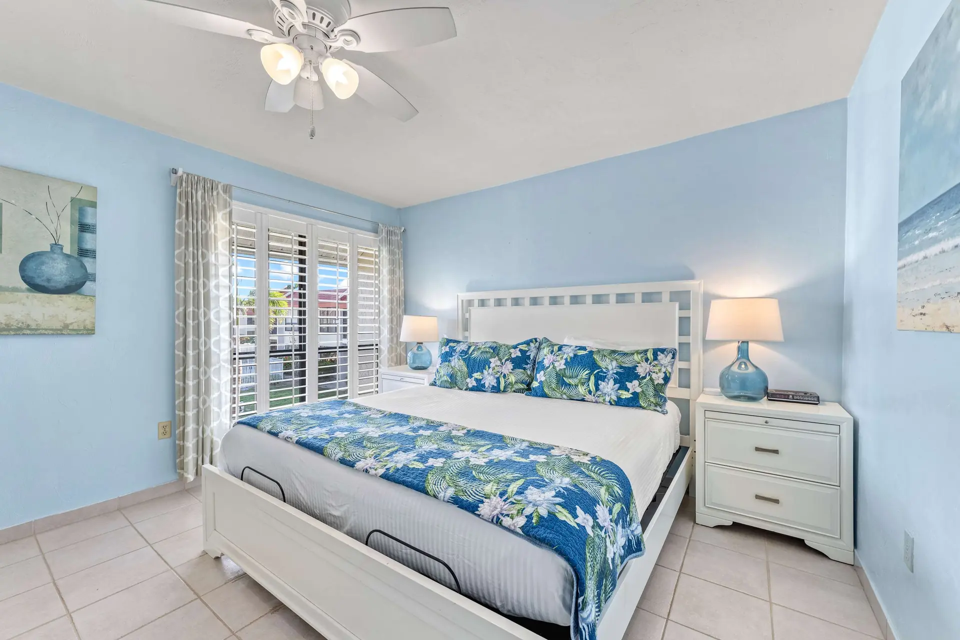 A bright bedroom with a king-size bed and blue floral accents.