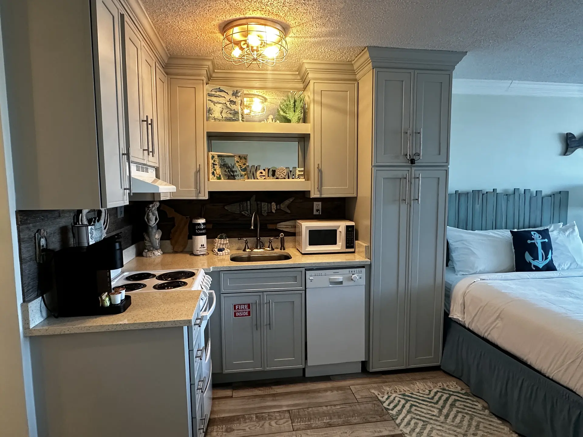 A compact kitchen area with a stove, sink, microwave, and cabinets.