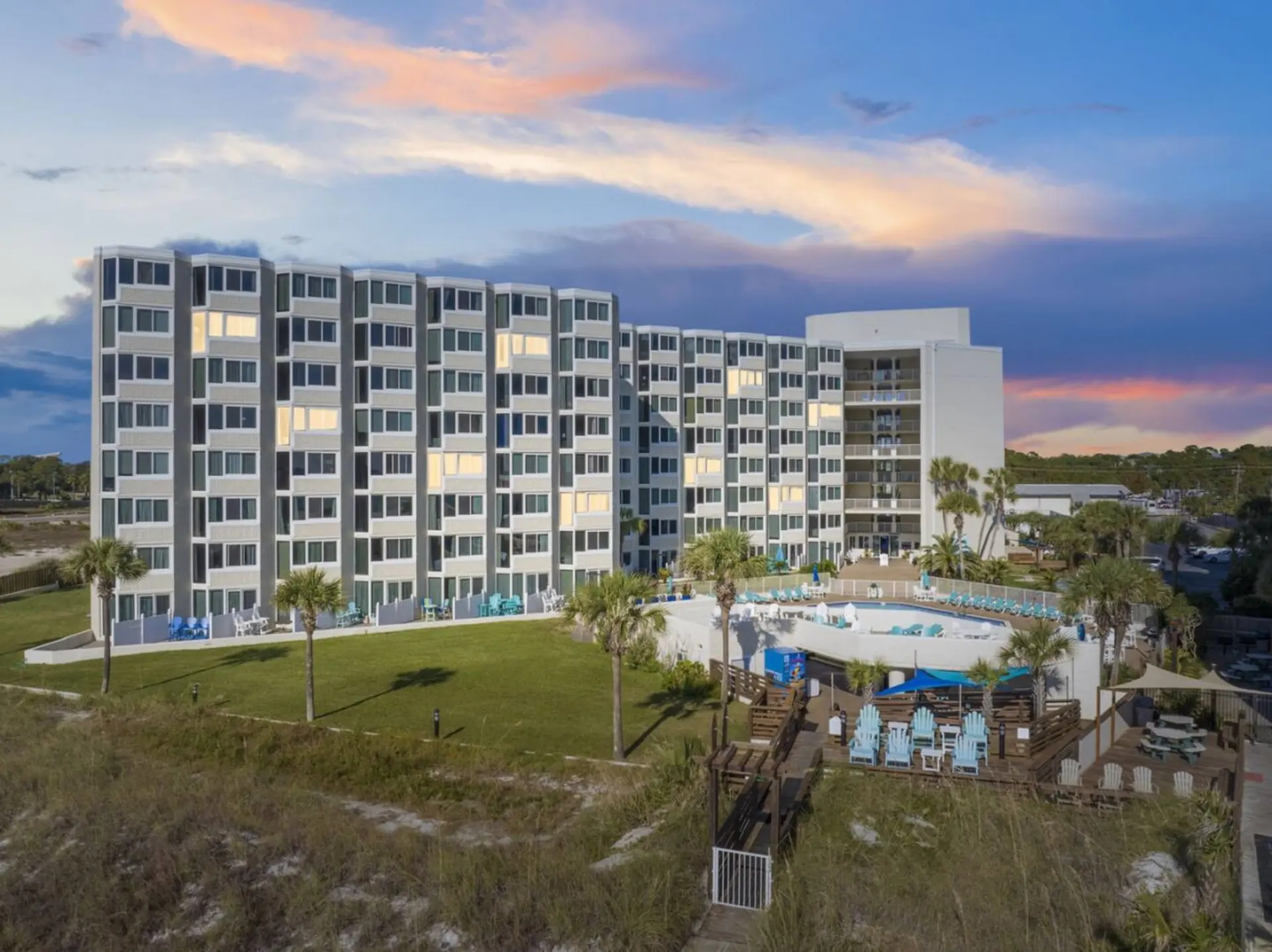 Resort building with pool and beach access at sunset.