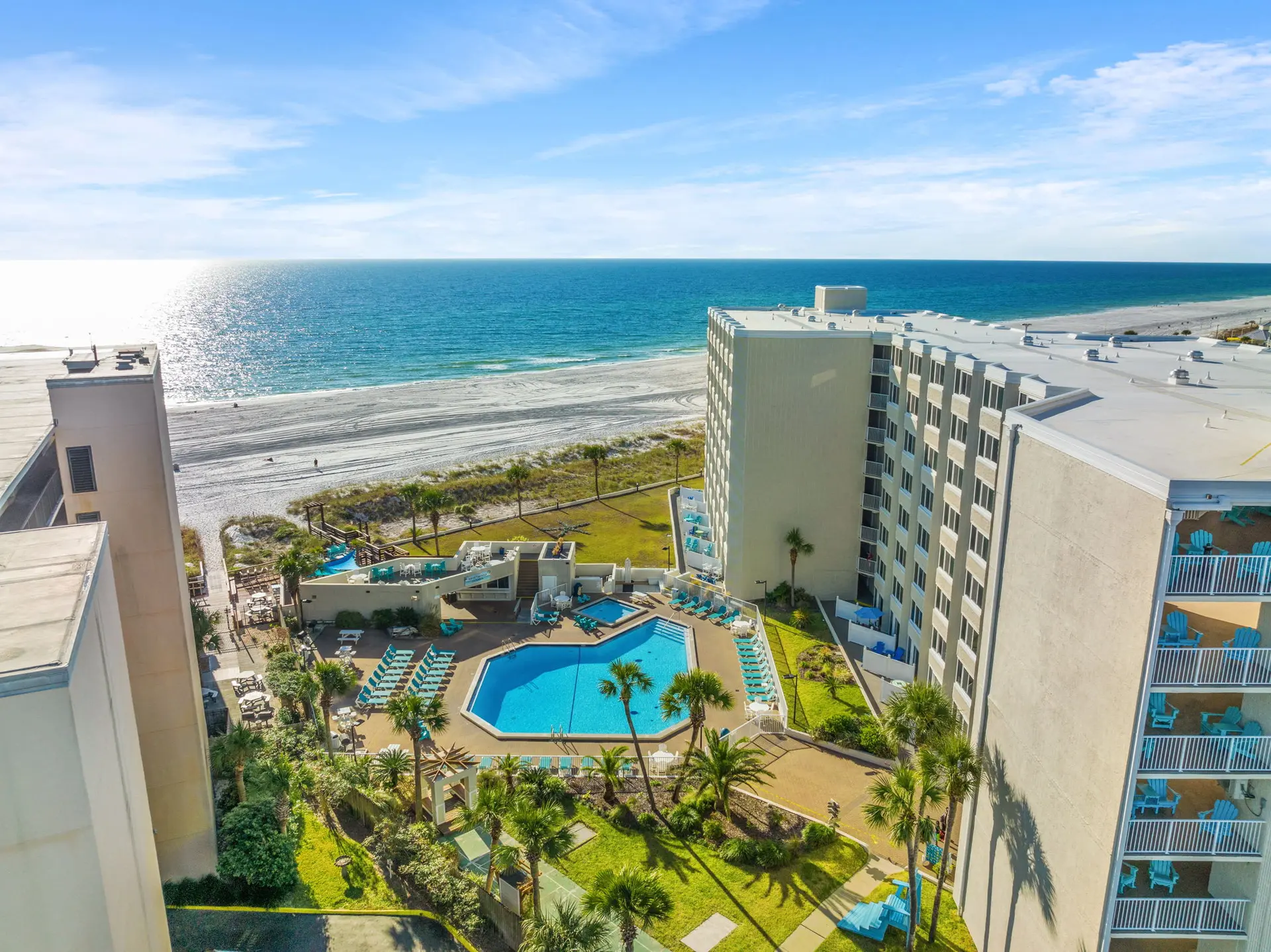 Oceanfront hotel with a pool, beach, and balconies overlooking the water.