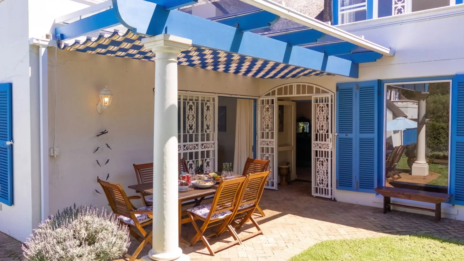 Outdoor patio with dining table, chairs, and blue shutters.