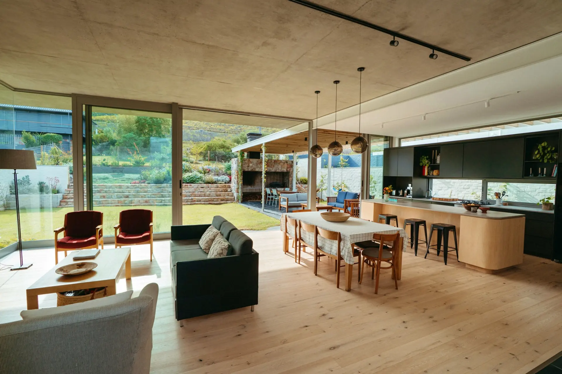 A modern open-plan living area with a kitchen, dining area, and lounge, opening onto a garden.