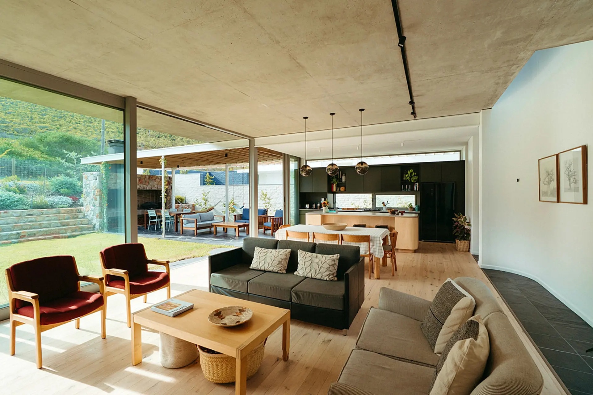 Modern open-plan living room with sofas, coffee table, dining area, and kitchen.