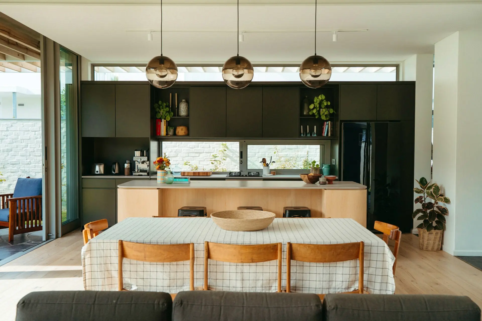 A modern dining room with a black kitchen island and pendant lights.