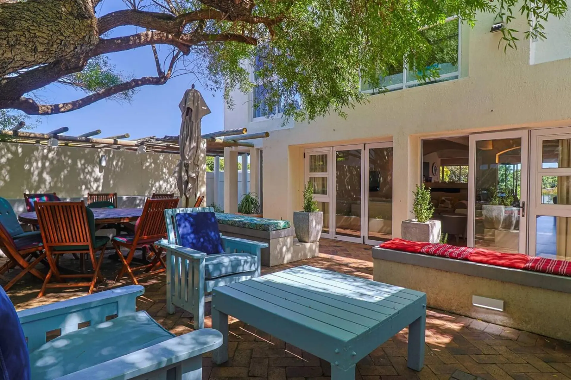 An outdoor patio with a dining set, seating, and a coffee table under a large tree.