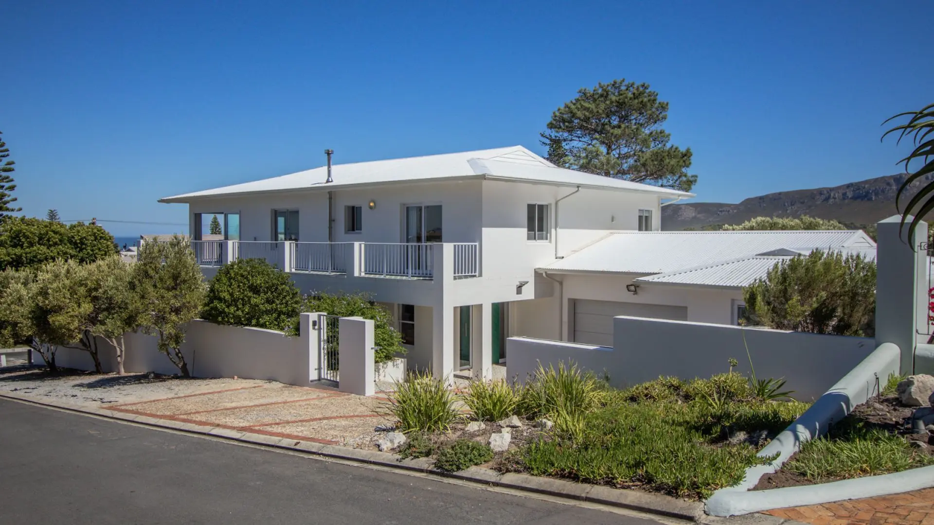 A white, modern house with a white roof and balcony.