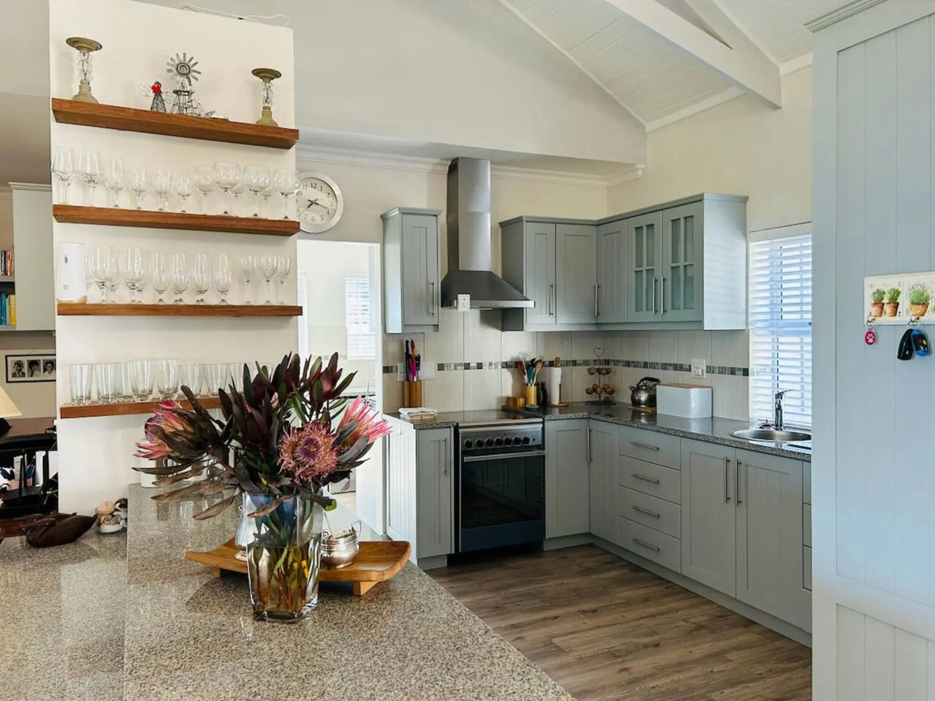 A modern kitchen with light gray cabinets and wooden floors.