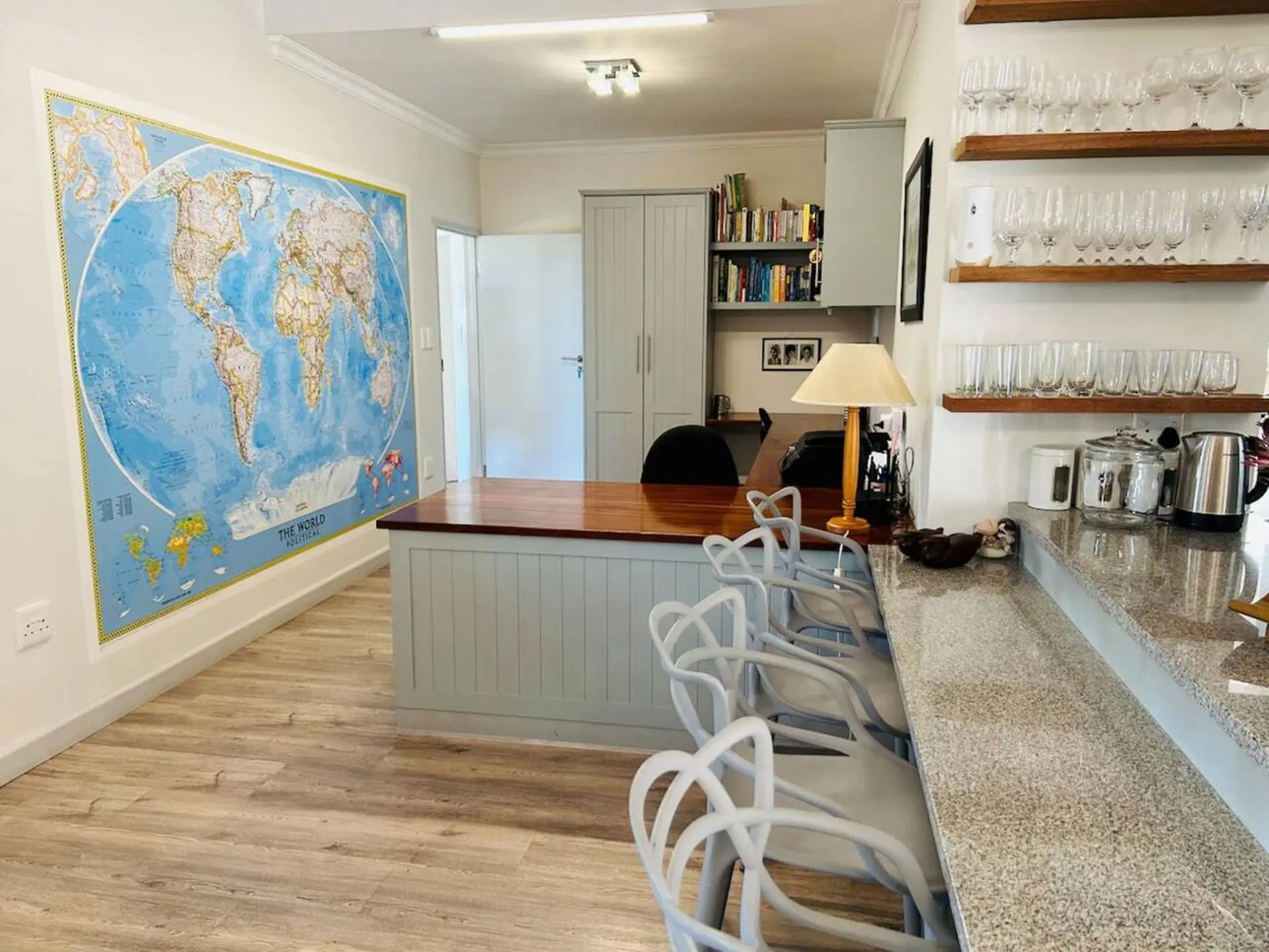A wide shot of a room with a world map on the wall and a kitchen counter.