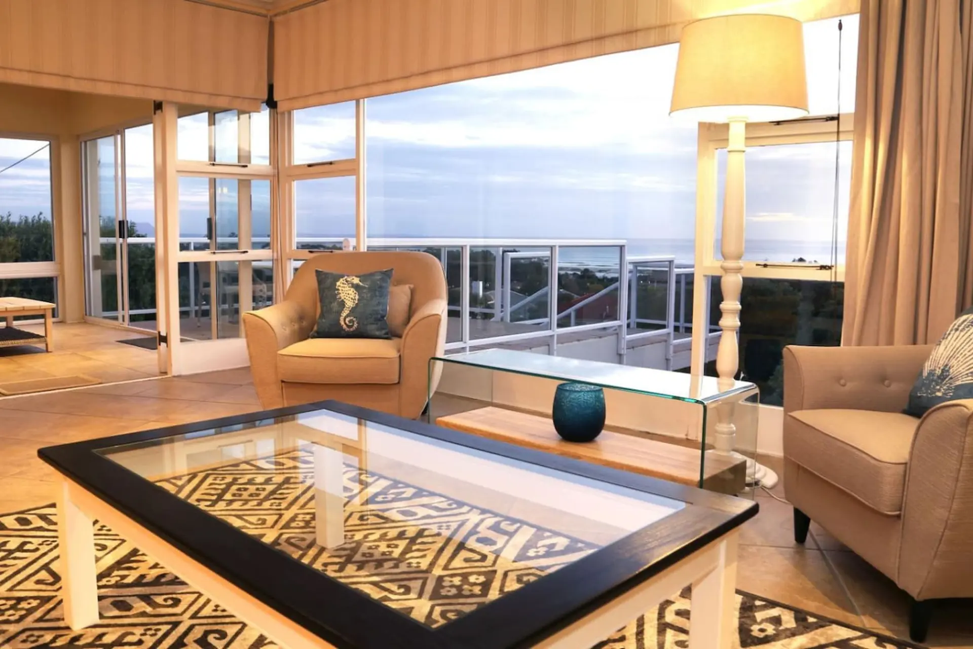 Sunlit living room with armchair, coffee table, and ocean view.