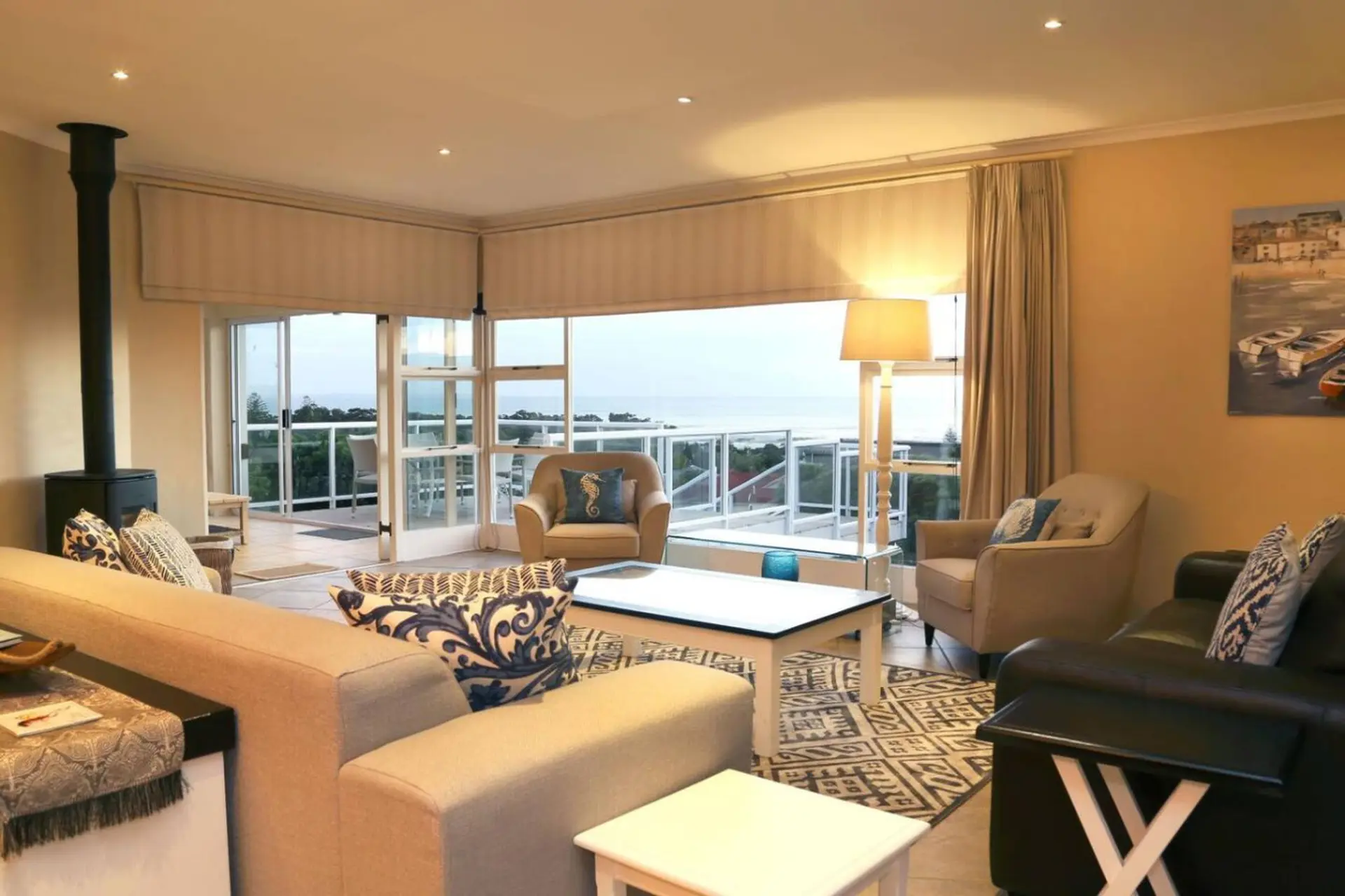 Living room with sofas, chairs, coffee table, and fireplace, overlooking the ocean.