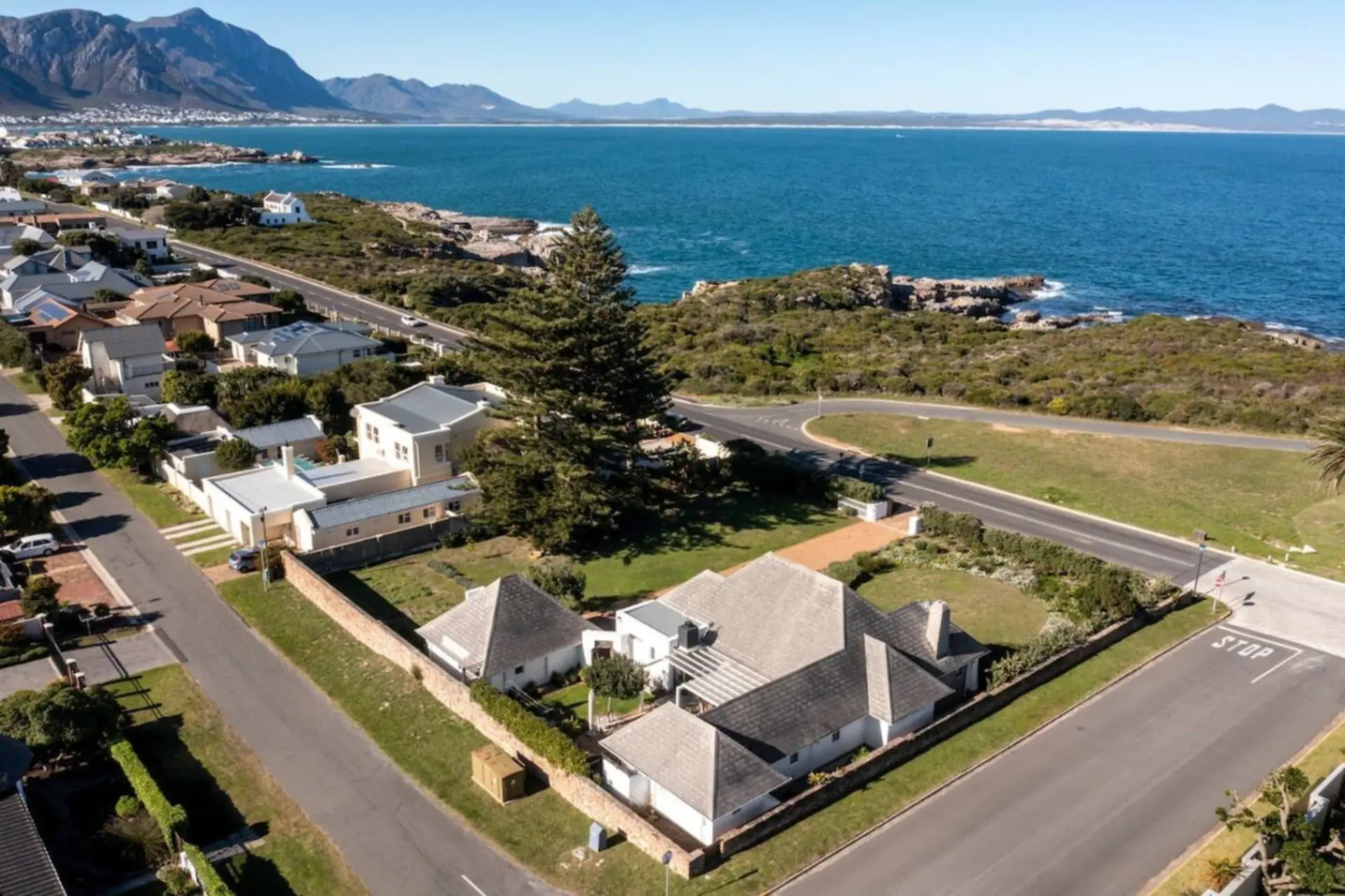 Aerial view of a coastal town with modern houses, a road, and the ocean.