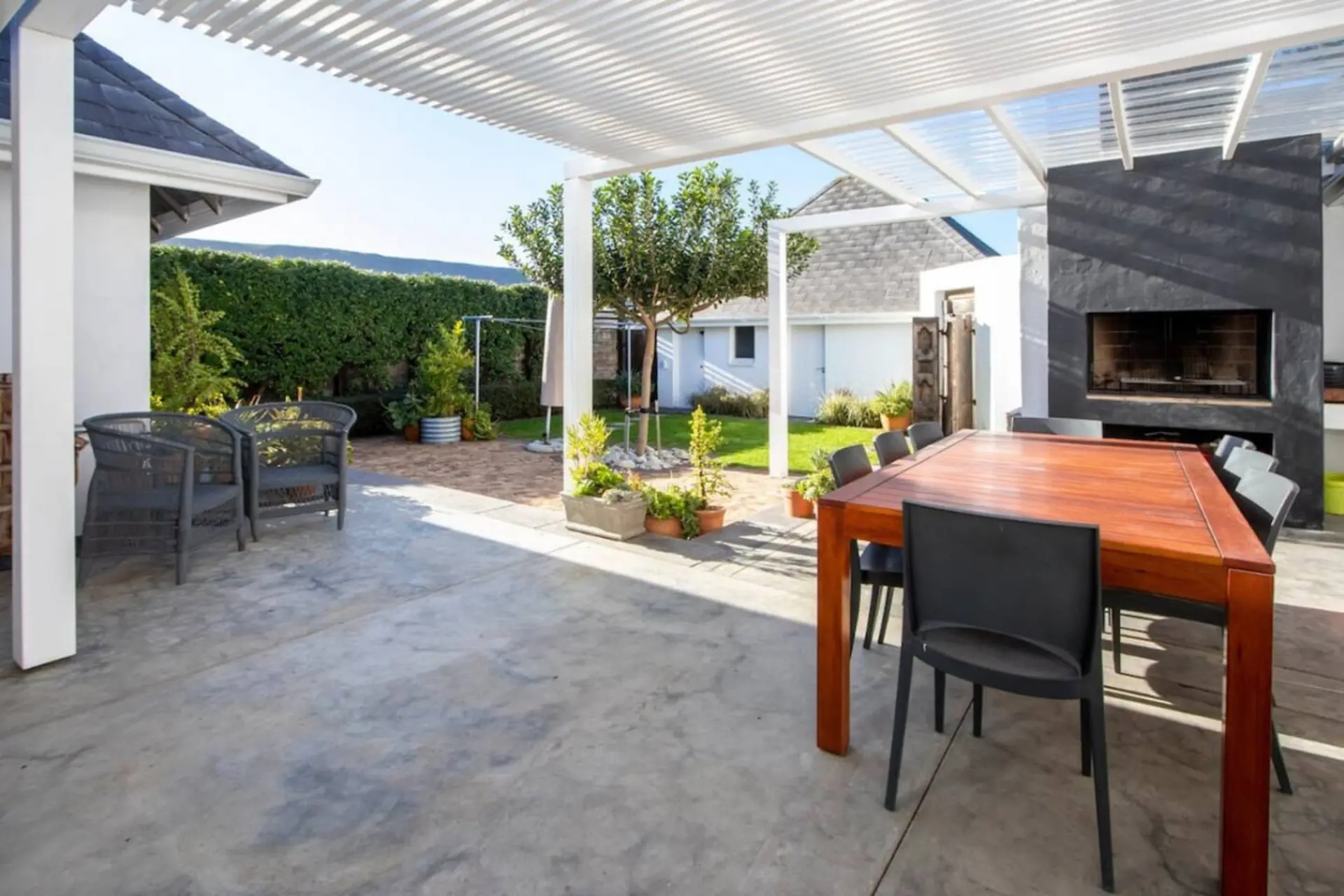 Outdoor patio with a wooden table and chairs, and a built-in fireplace.