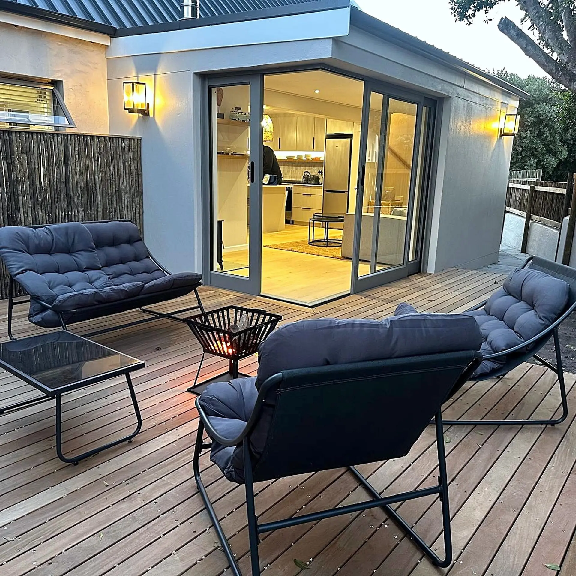 Outdoor patio with lounge chairs and a fire pit in front of a modern home.