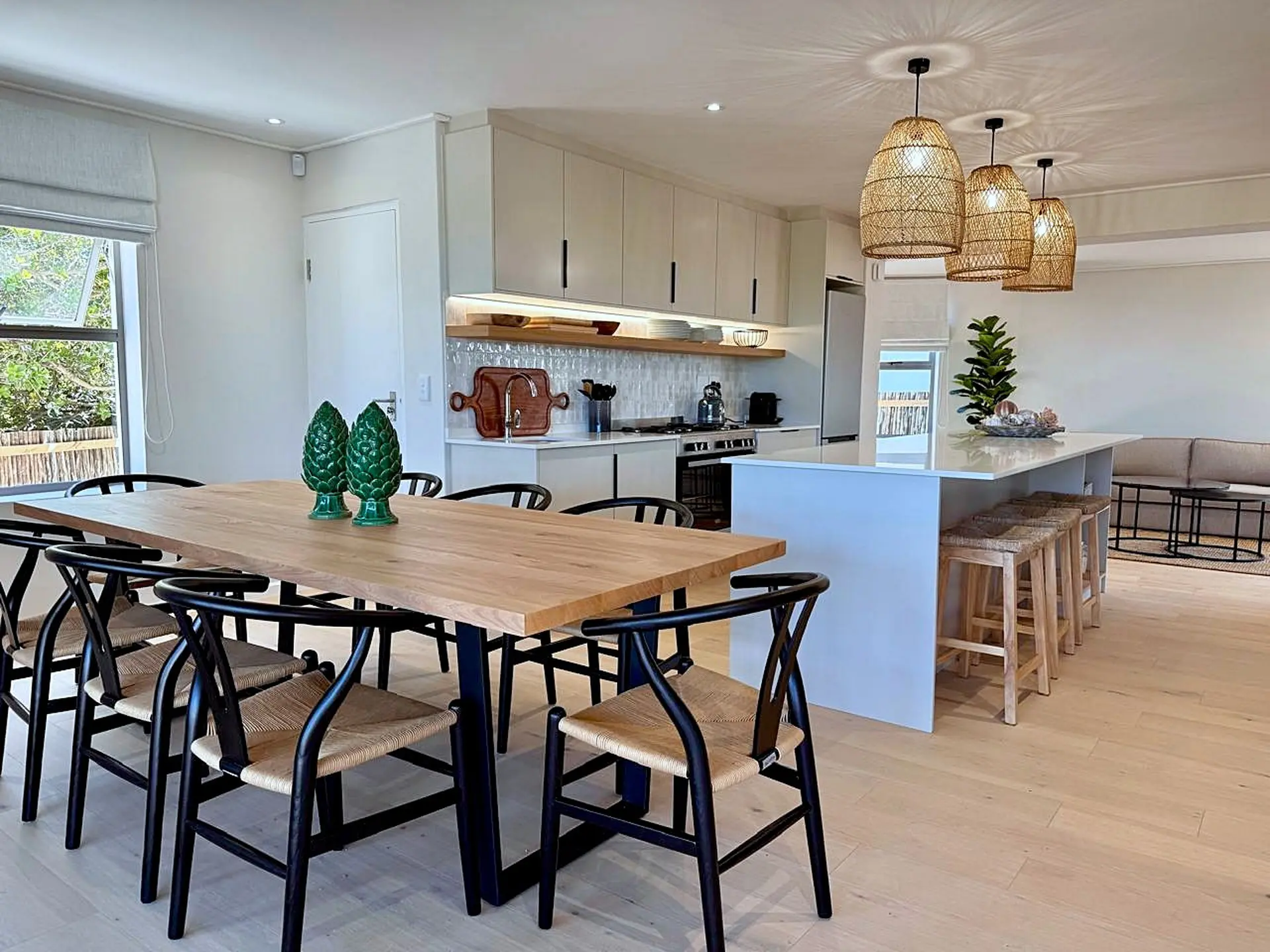 Modern dining room and kitchen with island, pendant lights, and a wooden table.