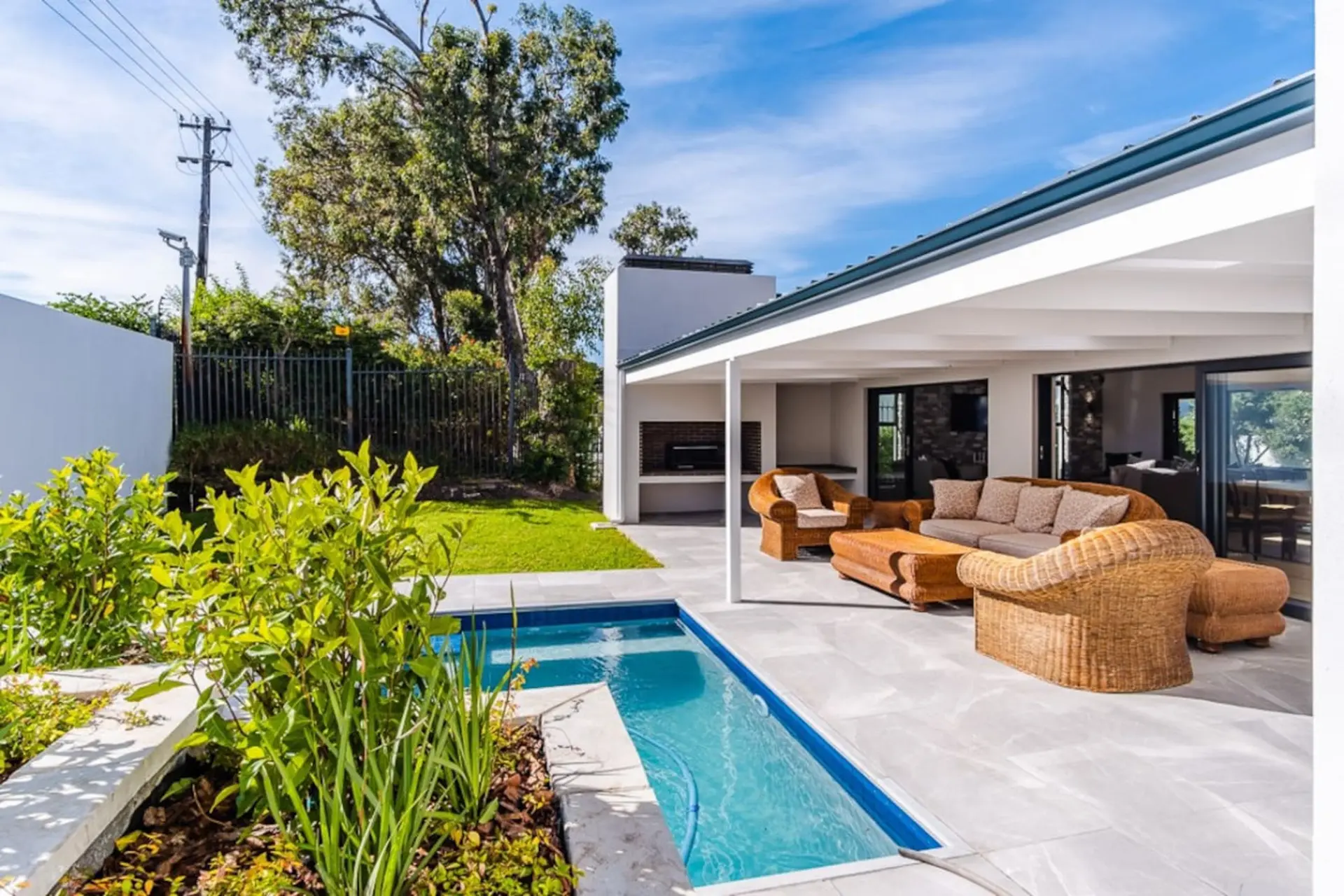 An outdoor patio with a pool, lounge chairs, a sofa, and a coffee table.