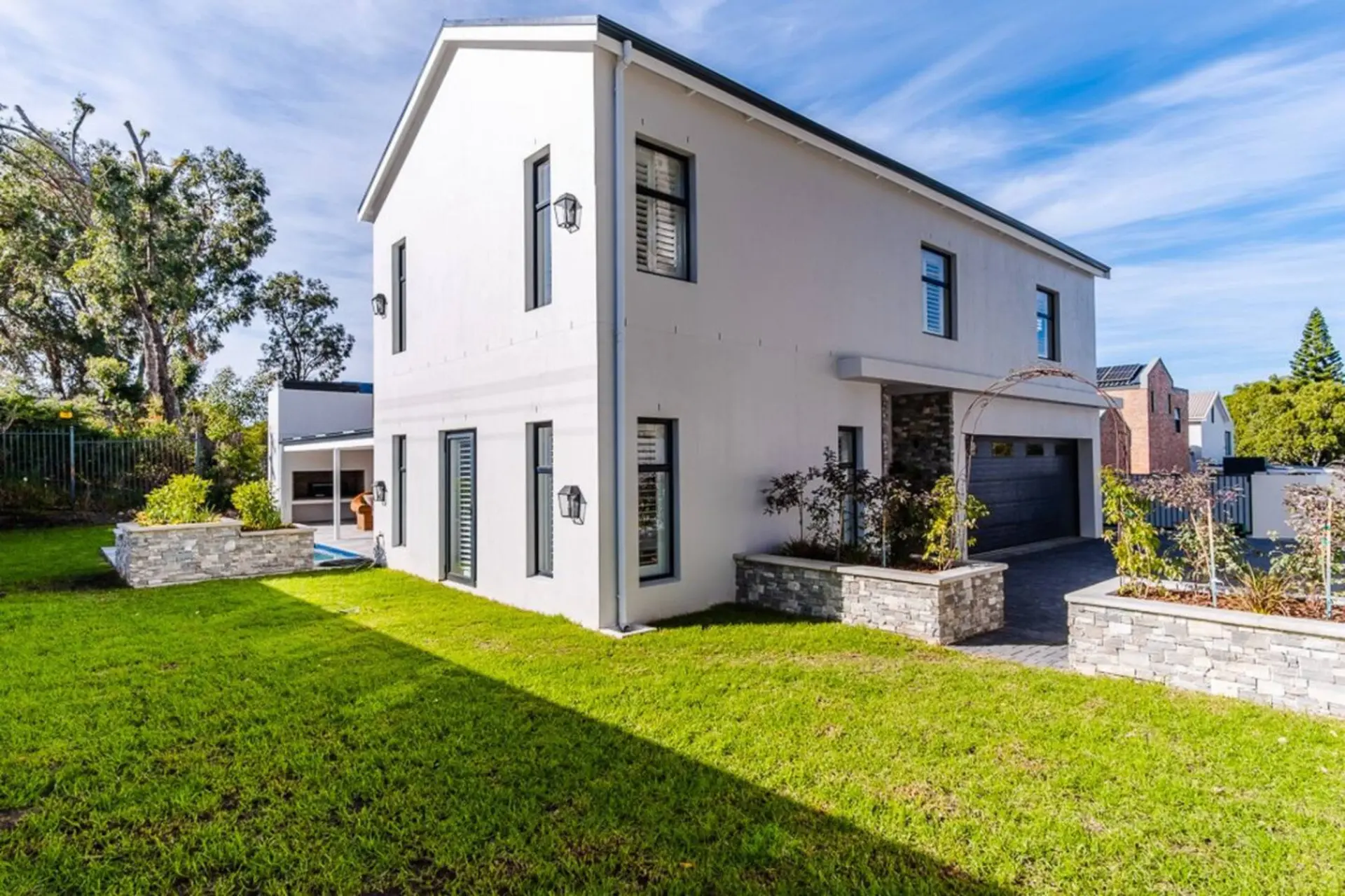 A modern white house with a garage and a green lawn.