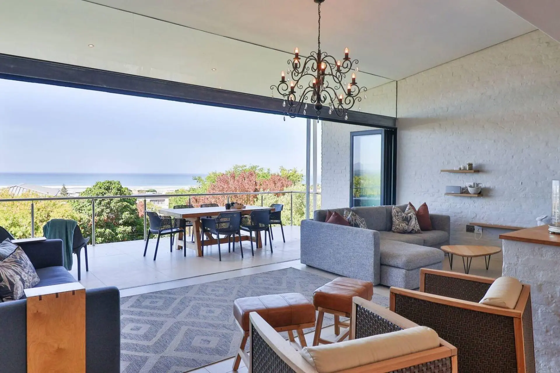 Modern living room with ocean view, dining table, and sectional sofa.