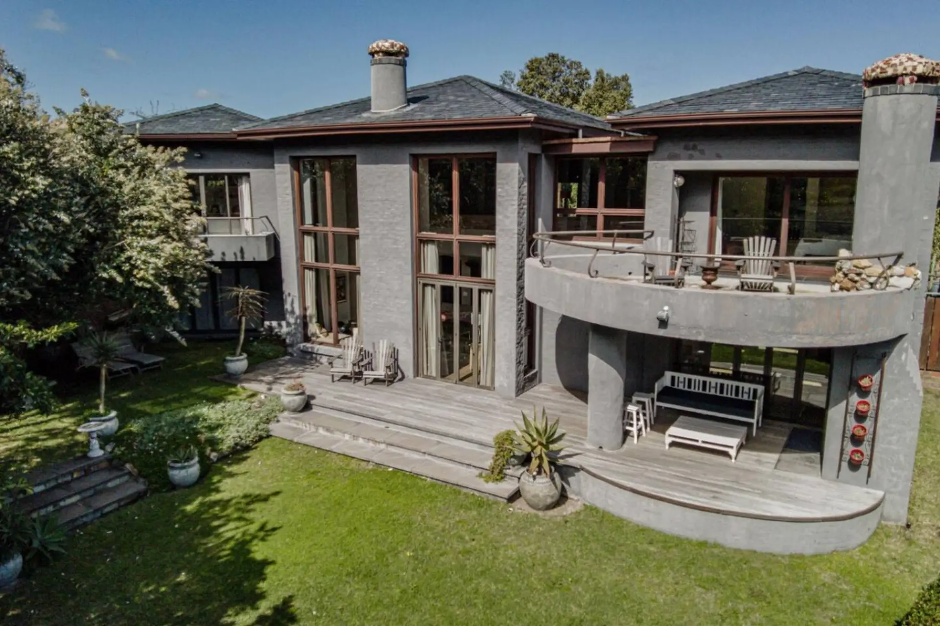 A modern grey house with large windows and a curved balcony.